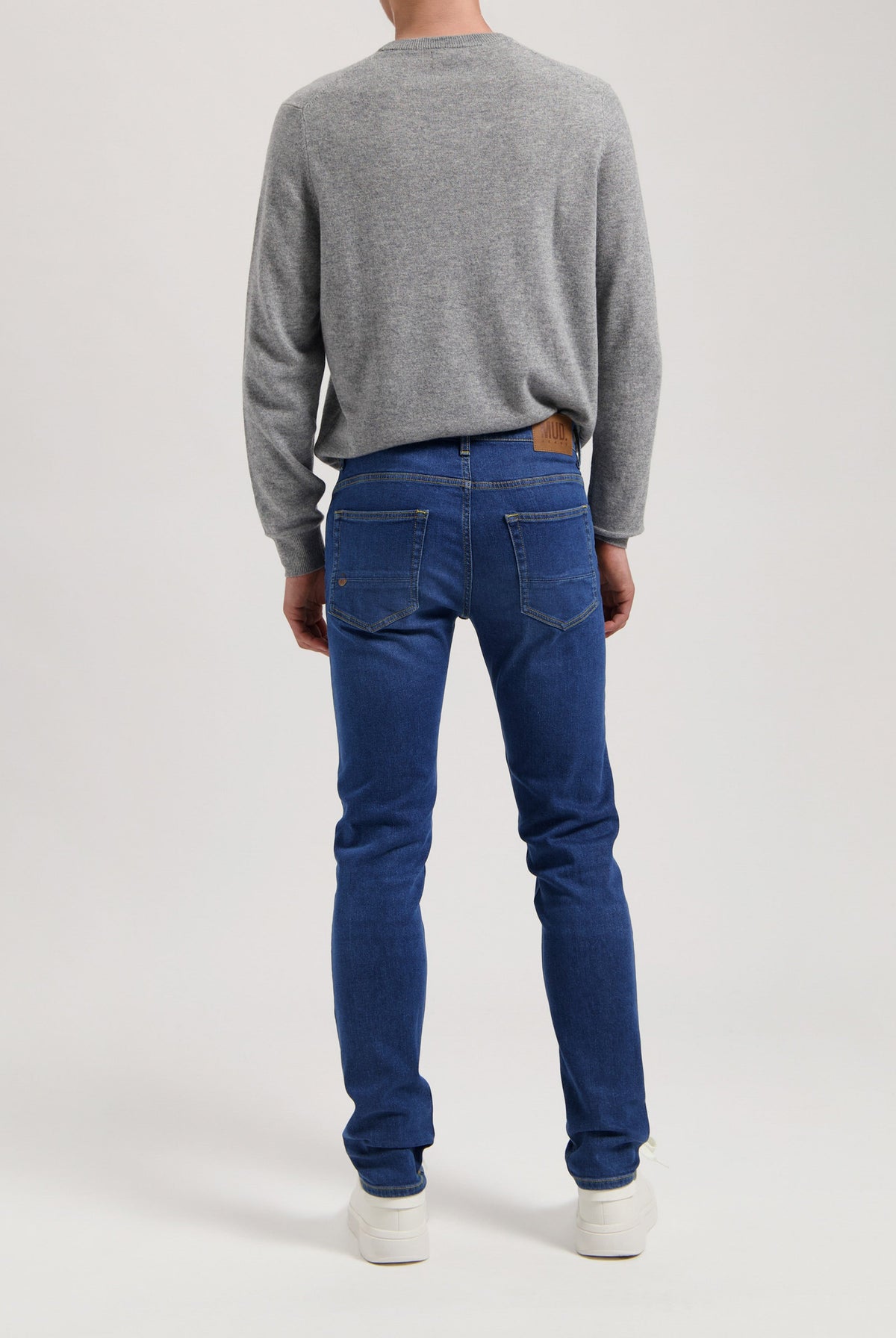Sustainable MUD Jeans denim jacket in deep blue, featuring front pockets and button closure, worn with blue denim jeans.
