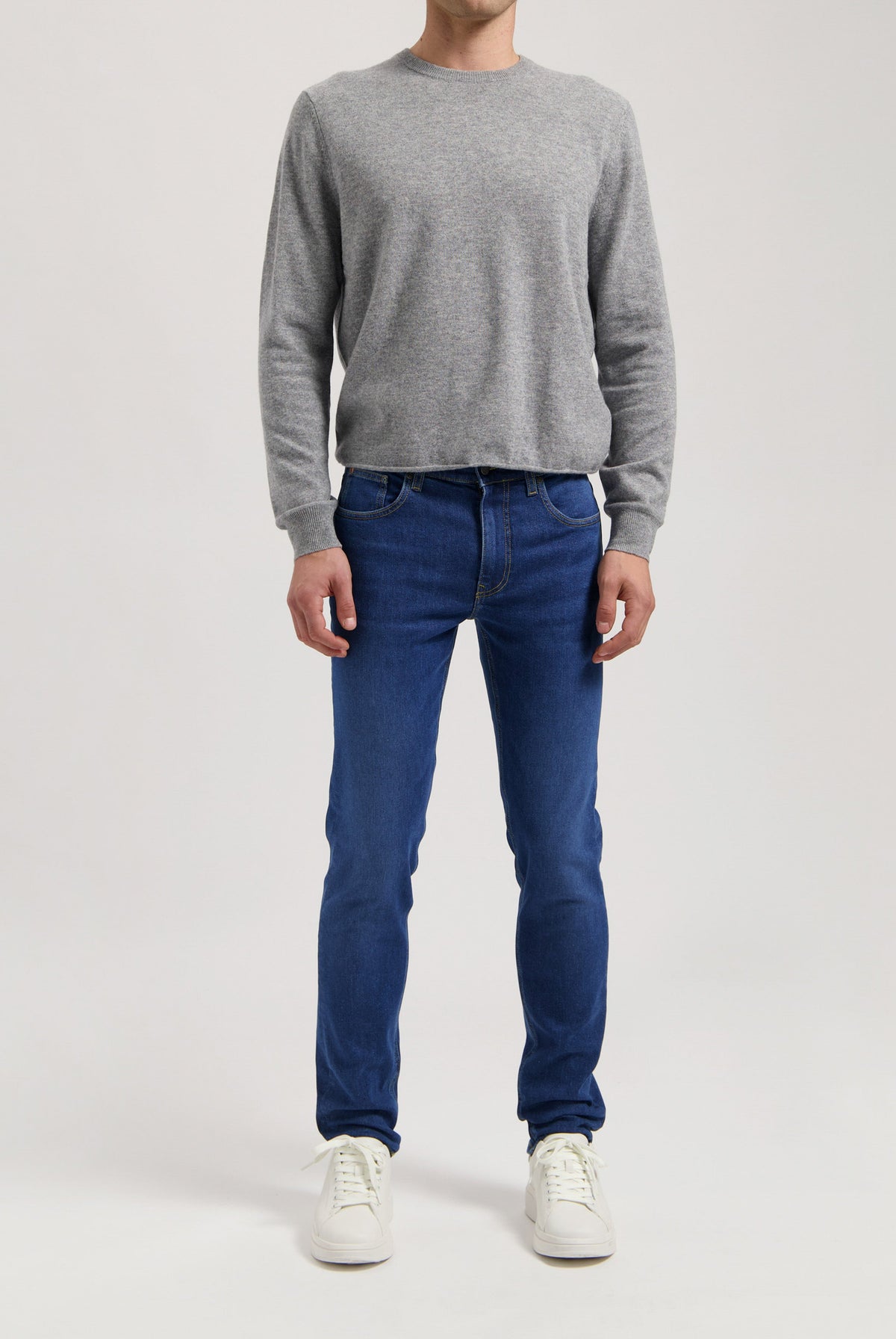 Sustainable MUD Jeans in deep blue denim, crafted ethically with organic cotton, paired with a casual gray t-shirt.