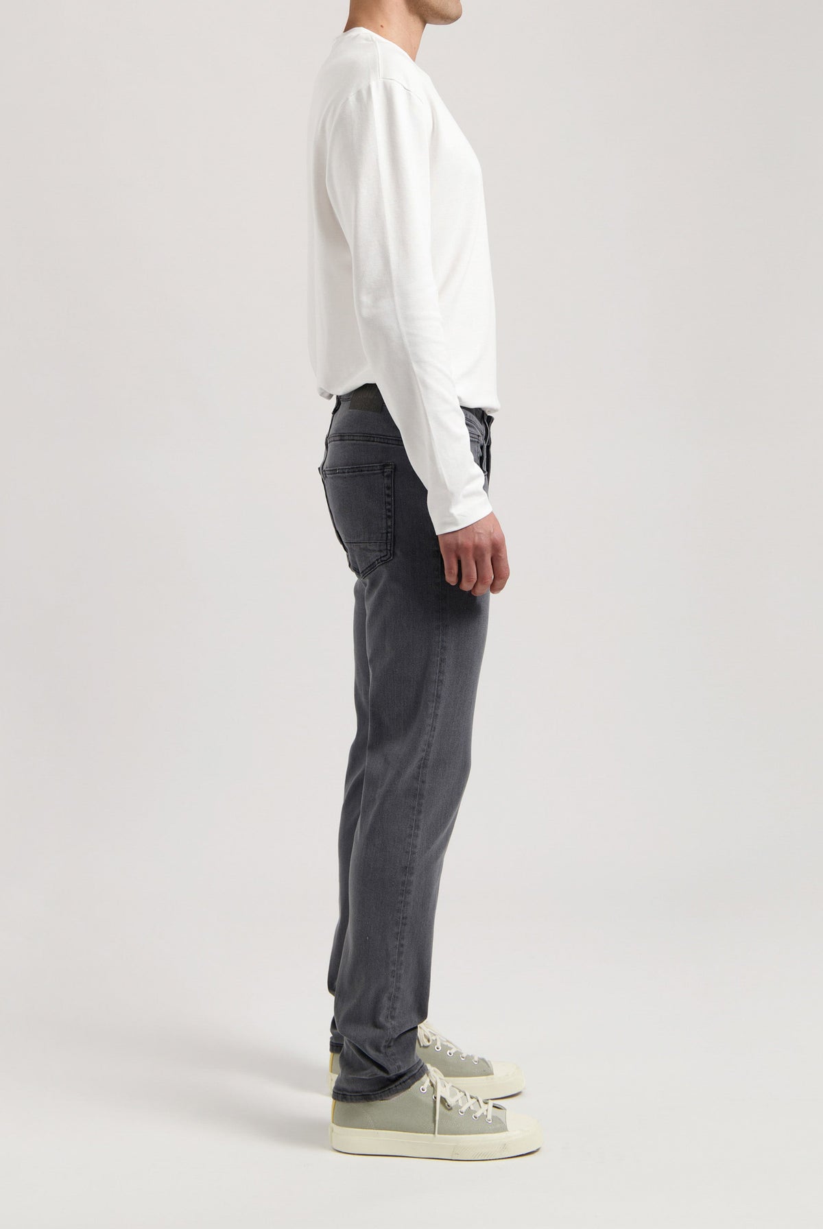Sustainable MUD Jeans in dark denim, crafted from ethical materials, paired with a light gray sweater.