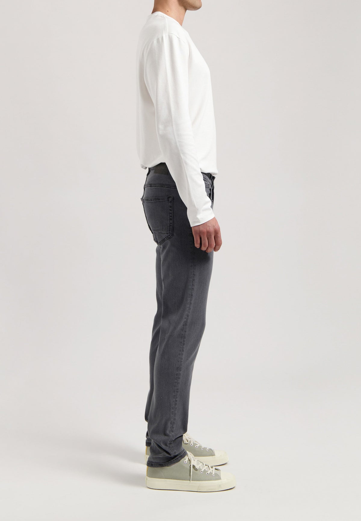 Sustainable MUD Jeans in dark denim, crafted from ethical materials, paired with a light gray sweater.