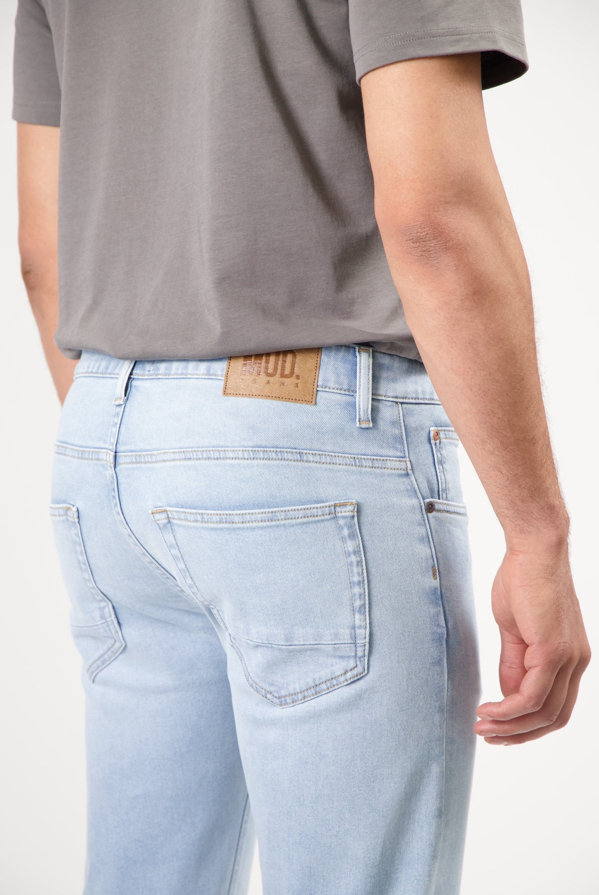 Sustainable MUD Jeans beige shorts, crafted from ethical materials, worn with a gray t-shirt and white sneakers.