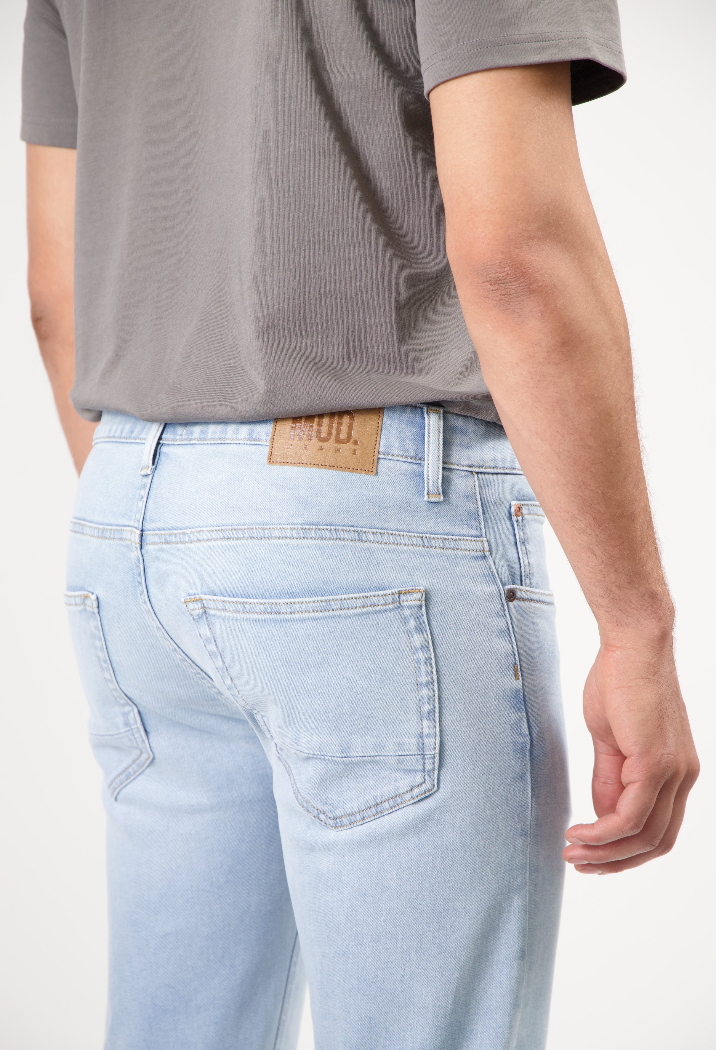 Sustainable MUD Jeans beige shorts, crafted from ethical materials, worn with a gray t-shirt and white sneakers.