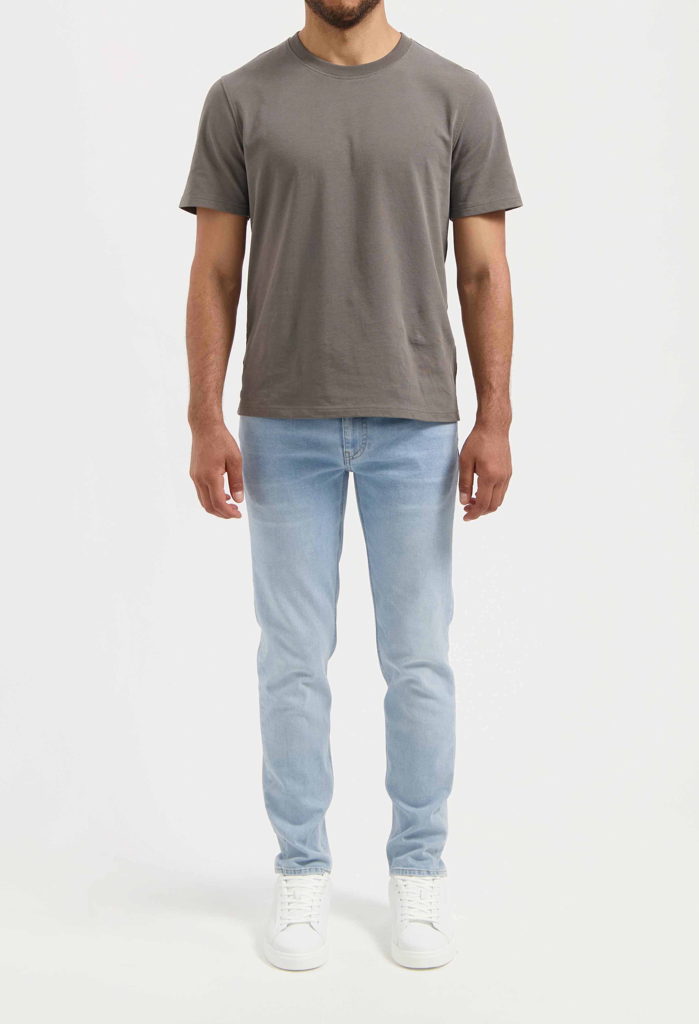 Sustainable MUD Jeans shorts in light blue denim, made from organic cotton, paired with a white T-shirt and sneakers.