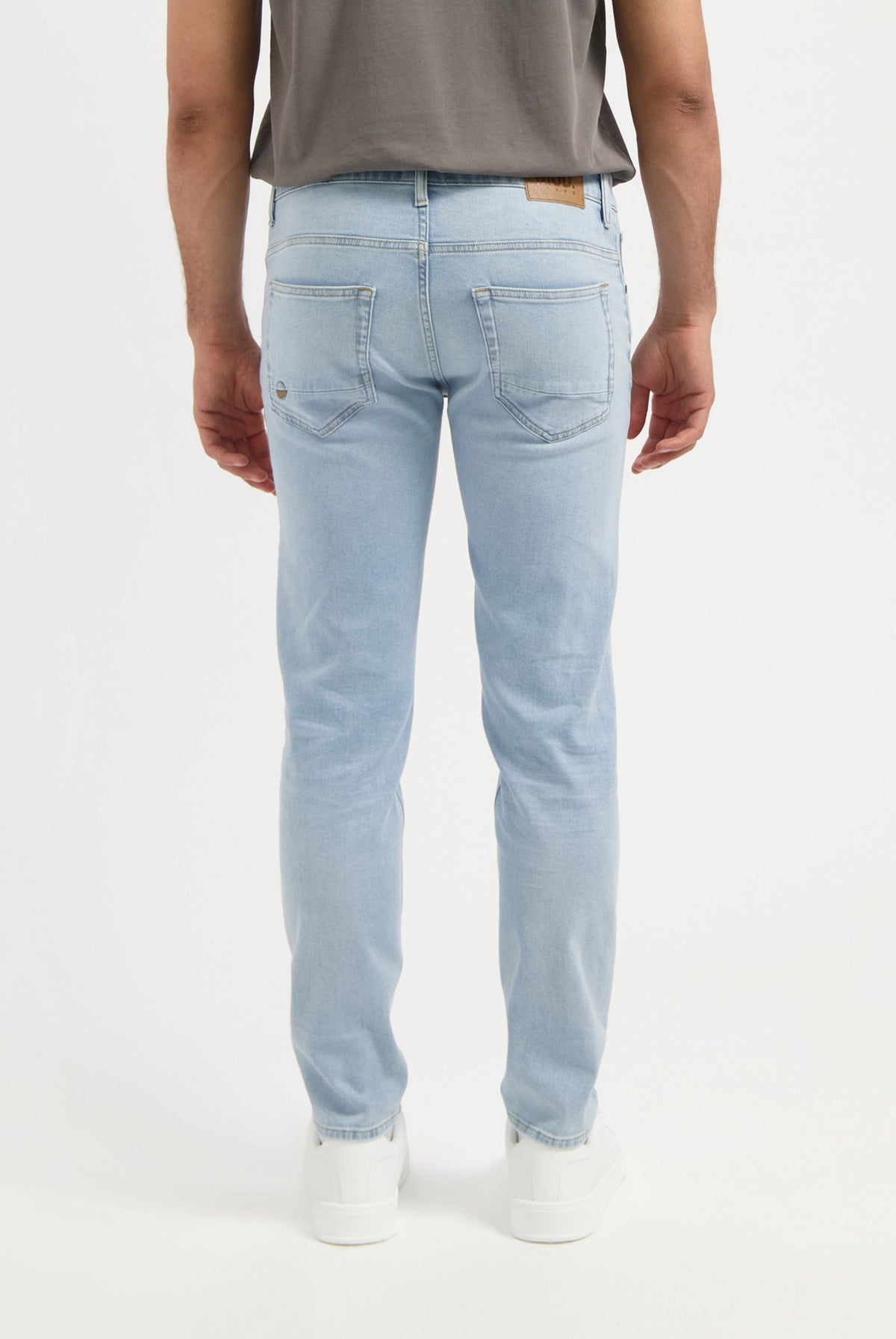 Sustainable MUD Jeans beige shorts made from eco-friendly materials, worn with gray shirt and white sneakers.