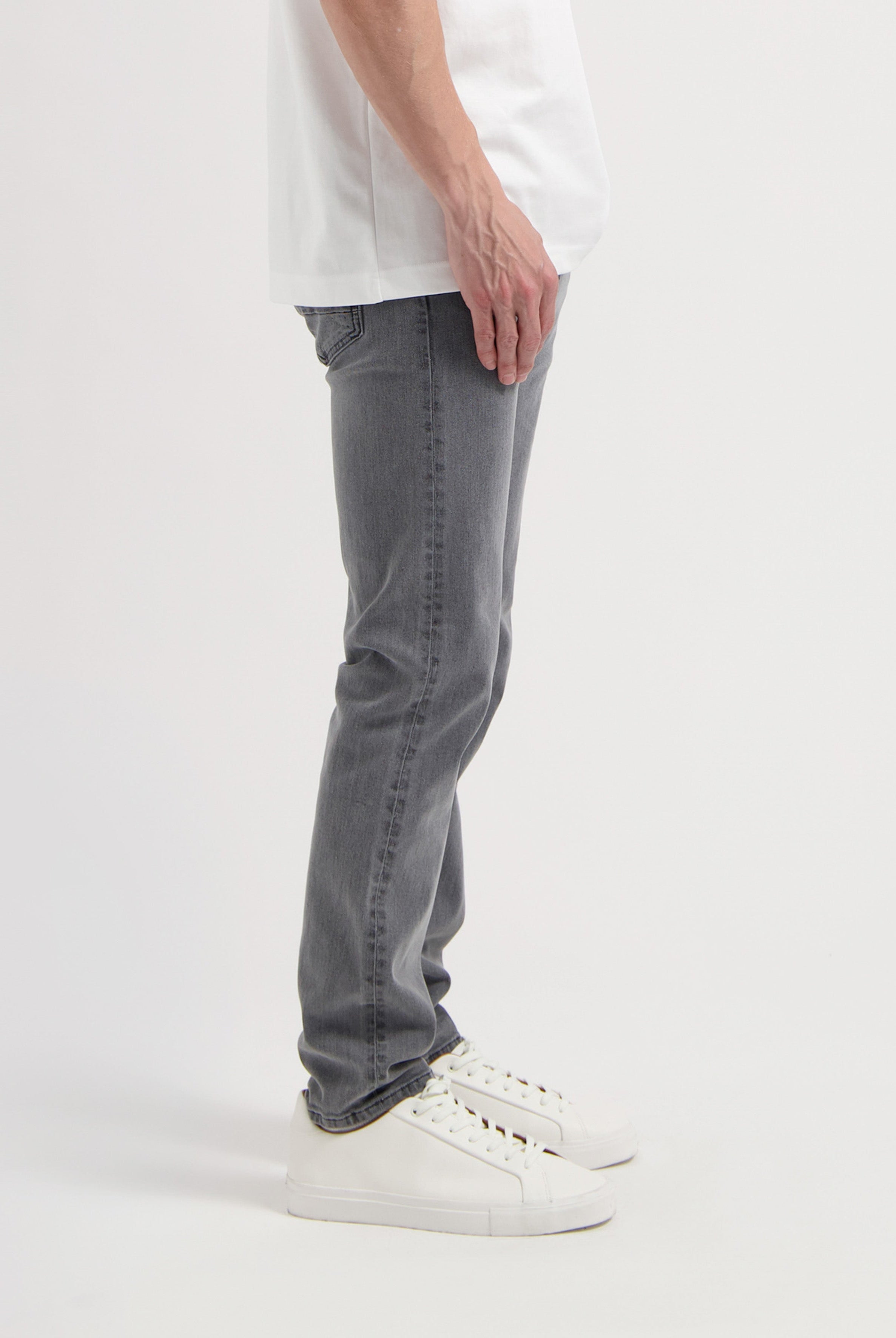 Sustainable MUD Jeans in gray denim, showcasing ethical design with a sleek fit, paired with a black top.