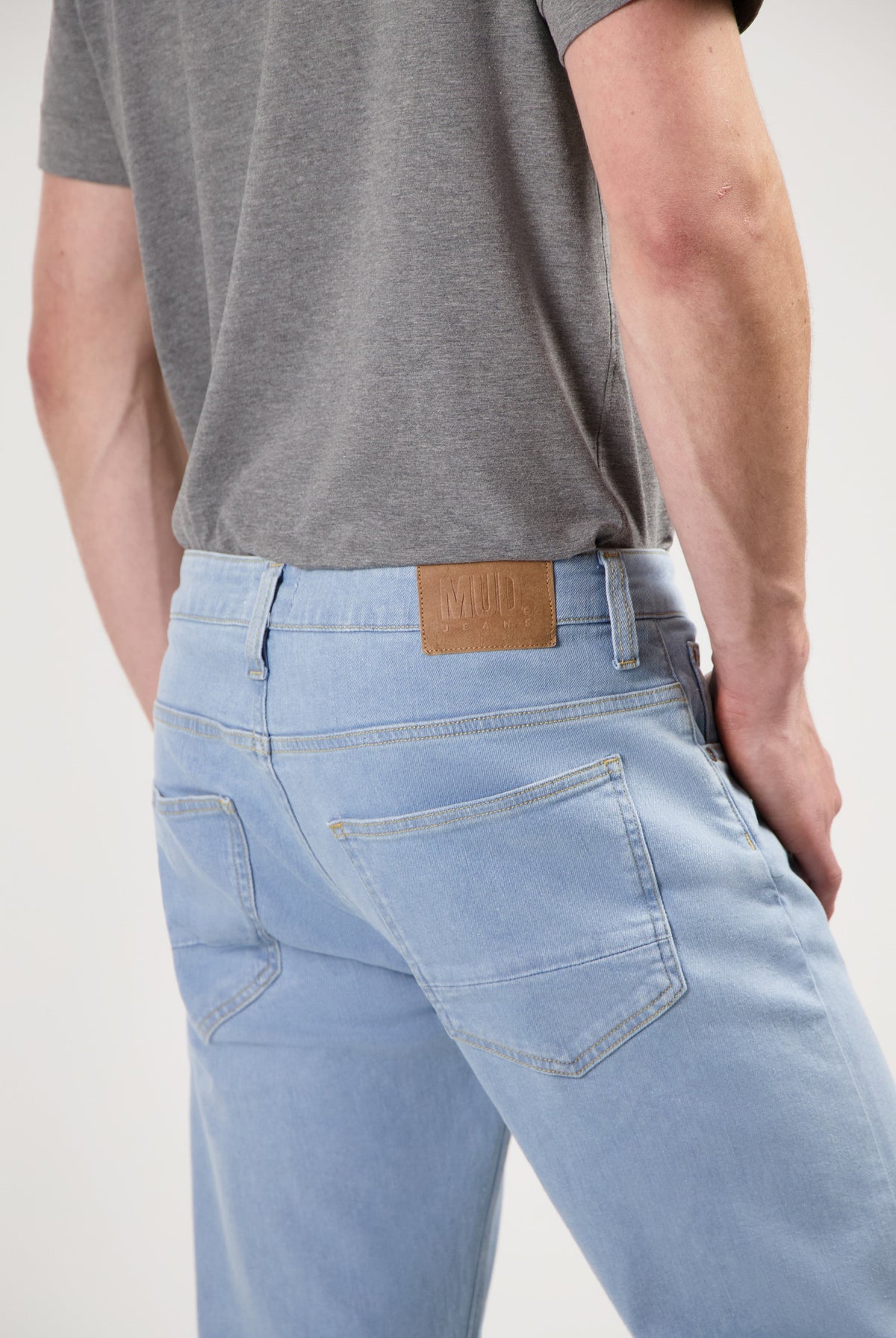 Sustainable MUD Jeans in dark gray denim, classic fit, paired with a black slogan sweatshirt and black sneakers.