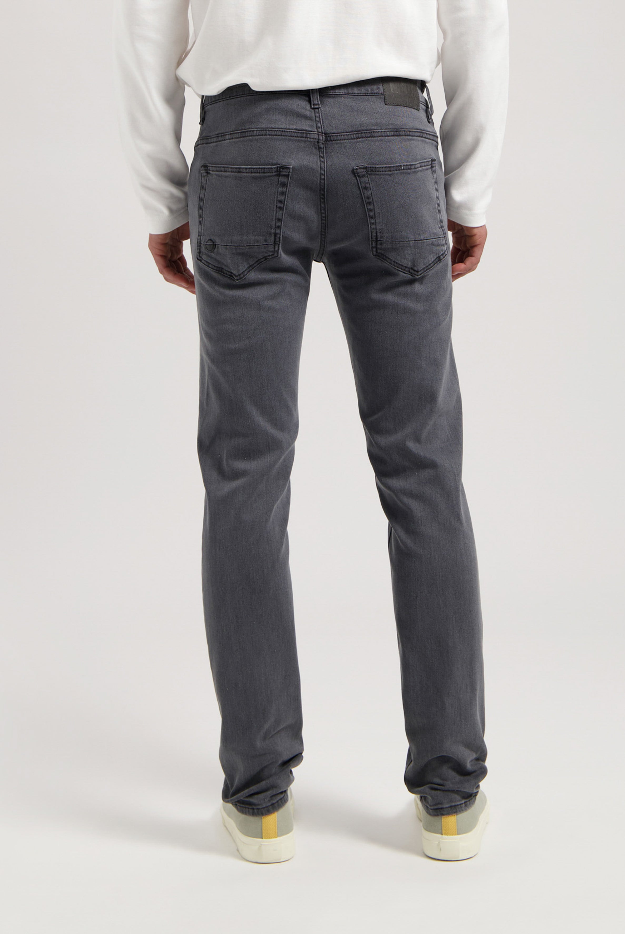 Sustainable MUD Jeans in classic blue denim, ethically made, styled with a white T-shirt and white sneakers.
