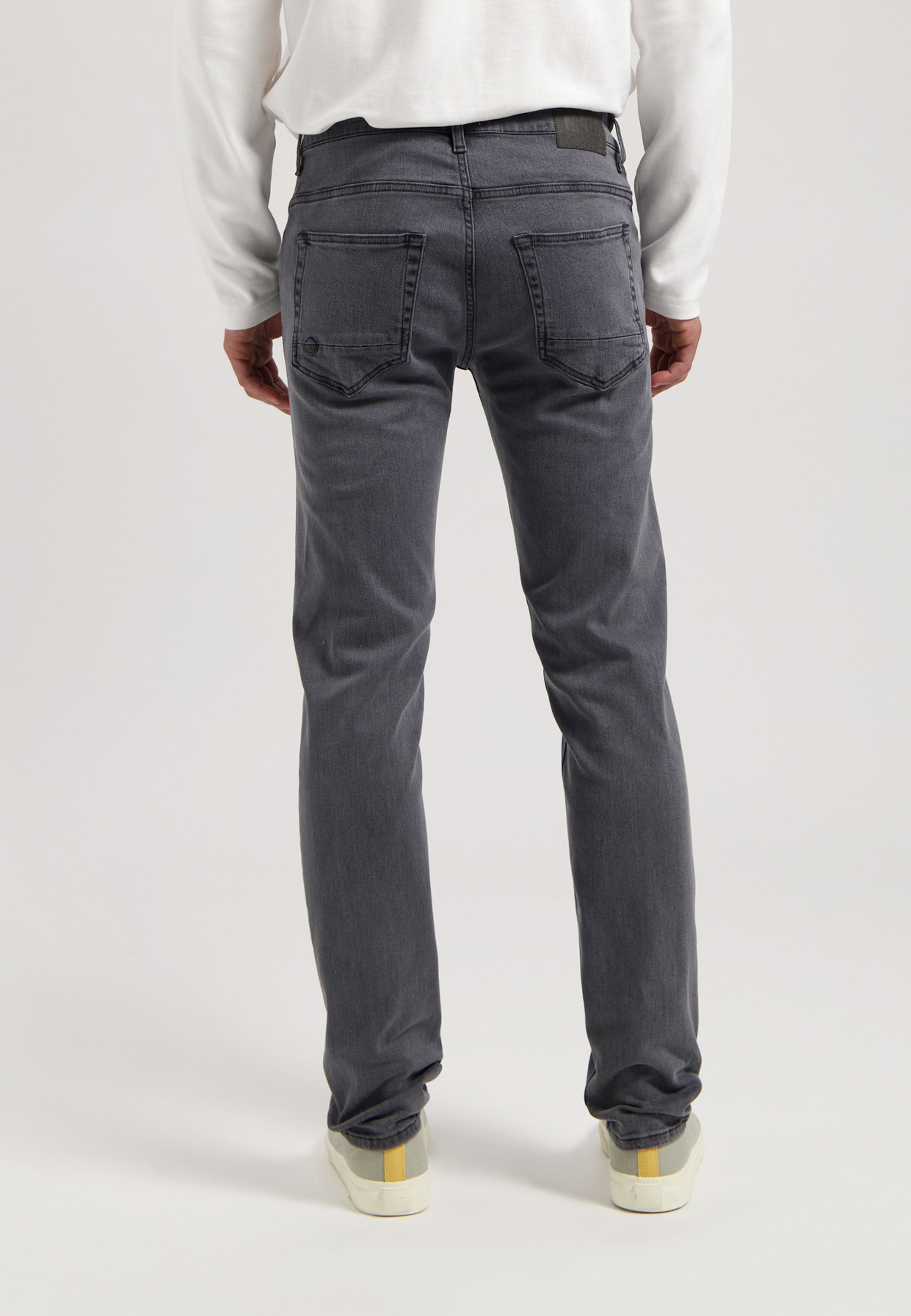 Sustainable MUD Jeans in classic blue denim, ethically made, styled with a white T-shirt and white sneakers.