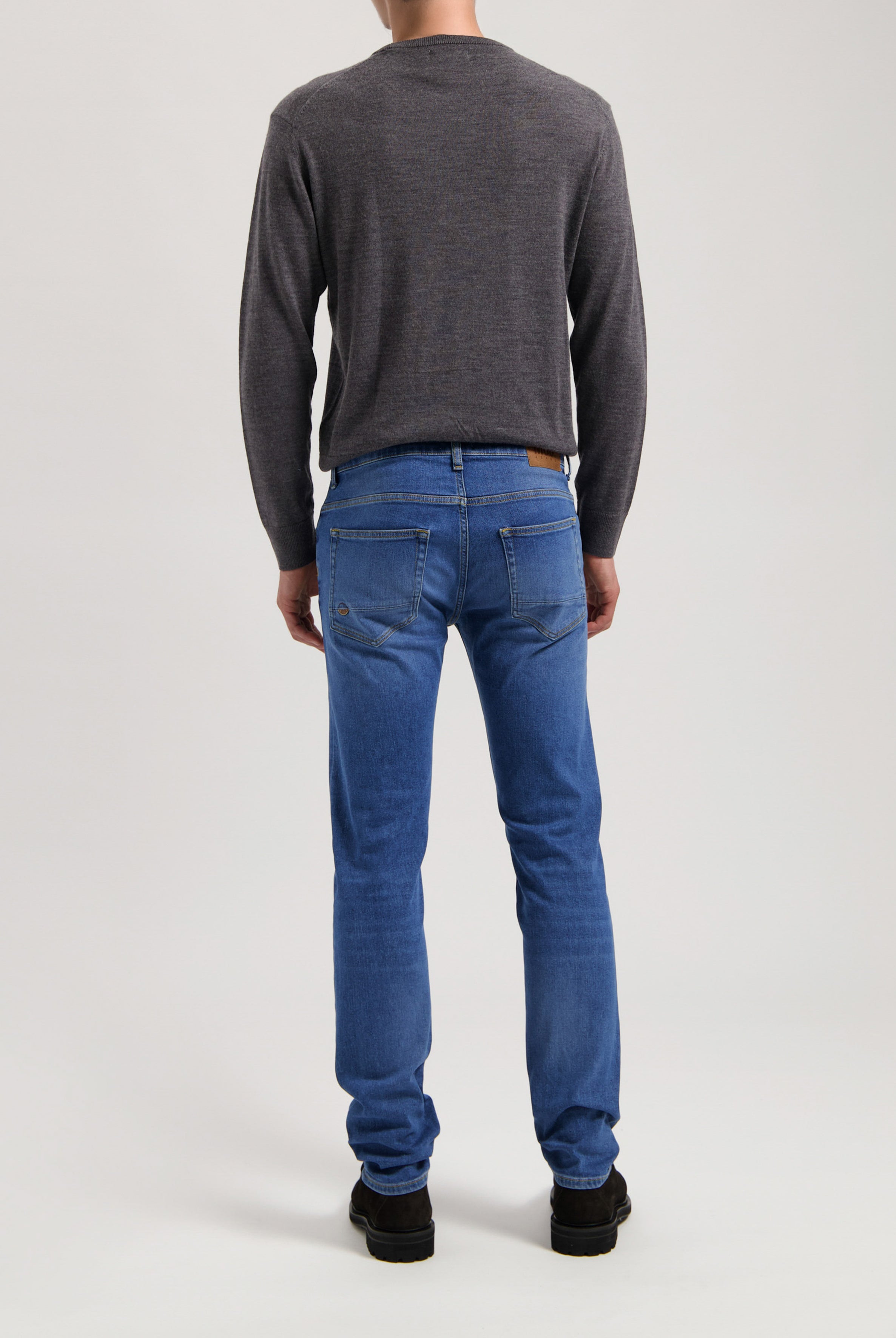 Sustainable MUD Jeans in dark blue denim, crafted ethically with organic materials, paired with a simple gray t-shirt.