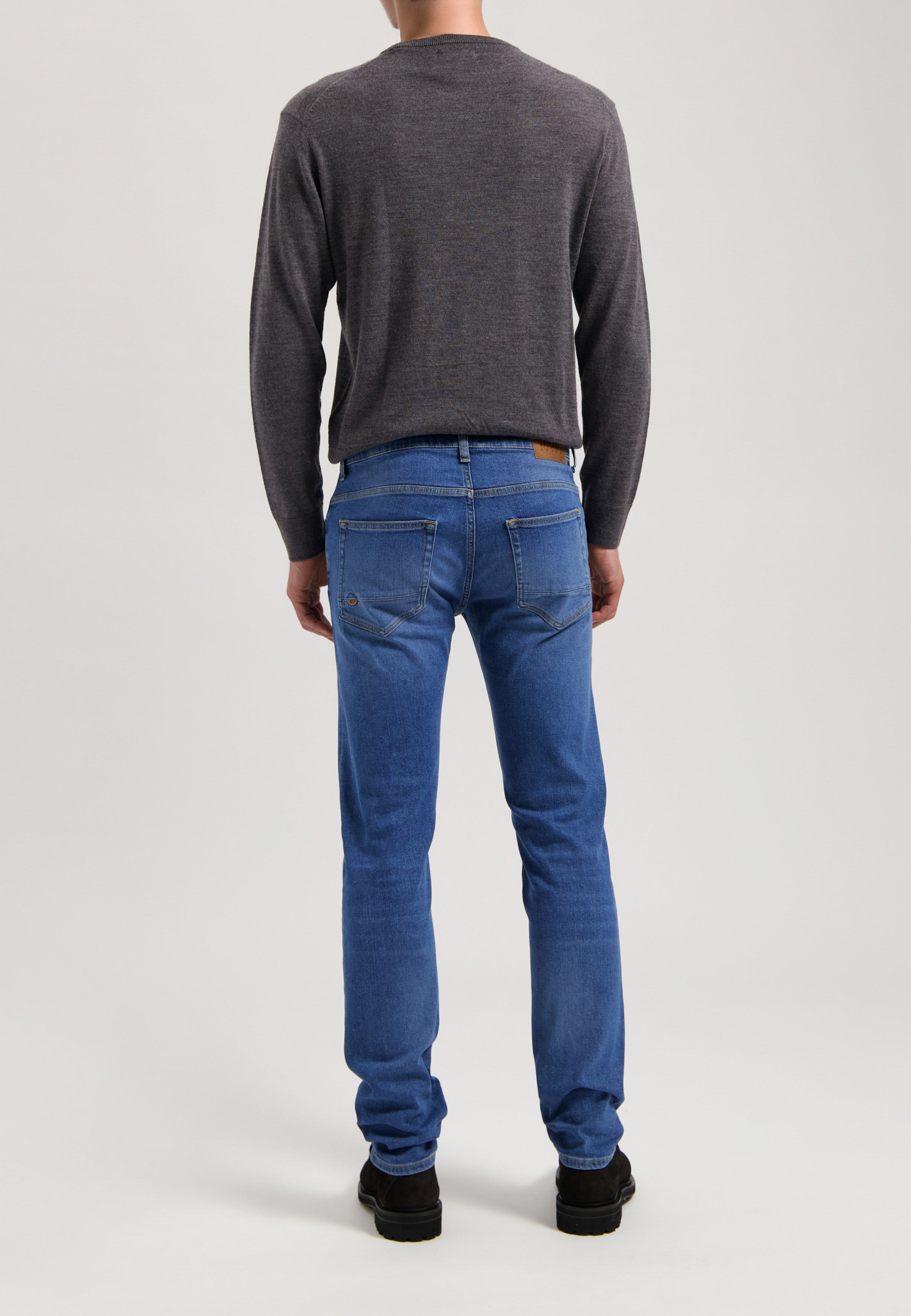 Sustainable MUD Jeans in dark blue denim, crafted ethically with organic materials, paired with a simple gray t-shirt.
