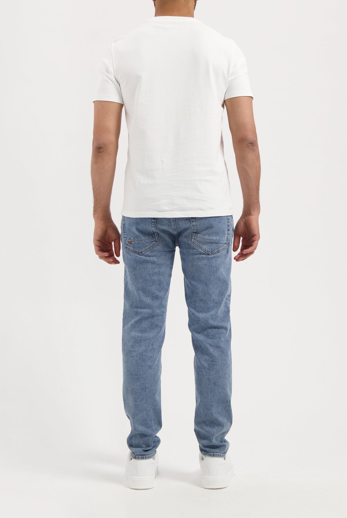 Sustainable MUD Jeans crafted from organic cotton in a modern blue short design, paired with a black tee and white sneakers.