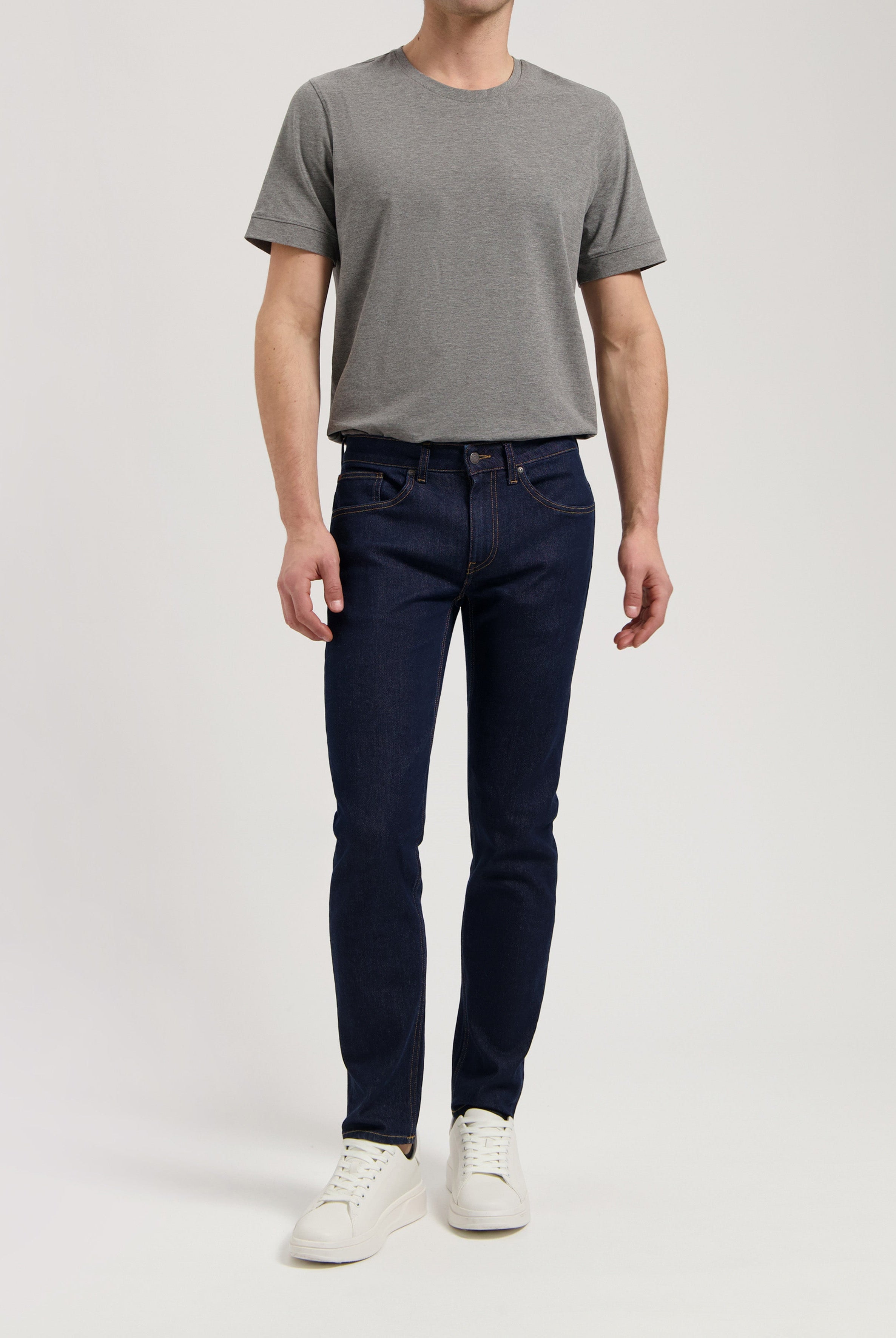 Sustainable MUD Jeans in a dark wash, crafted from organic materials, paired with a stylish gray sweater.