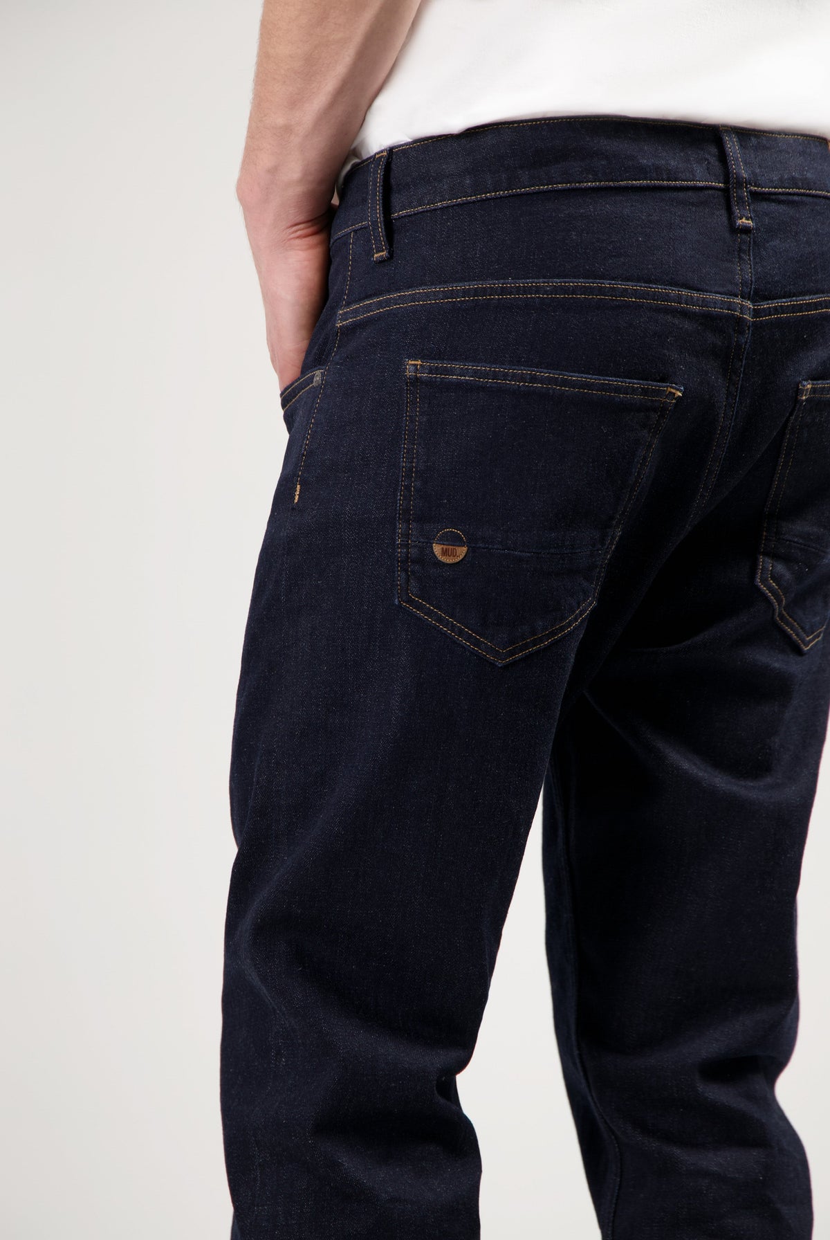 Eco-friendly MUD Jeans in blue denim, designed for a sustainable lifestyle, paired with a dark gray sweater.