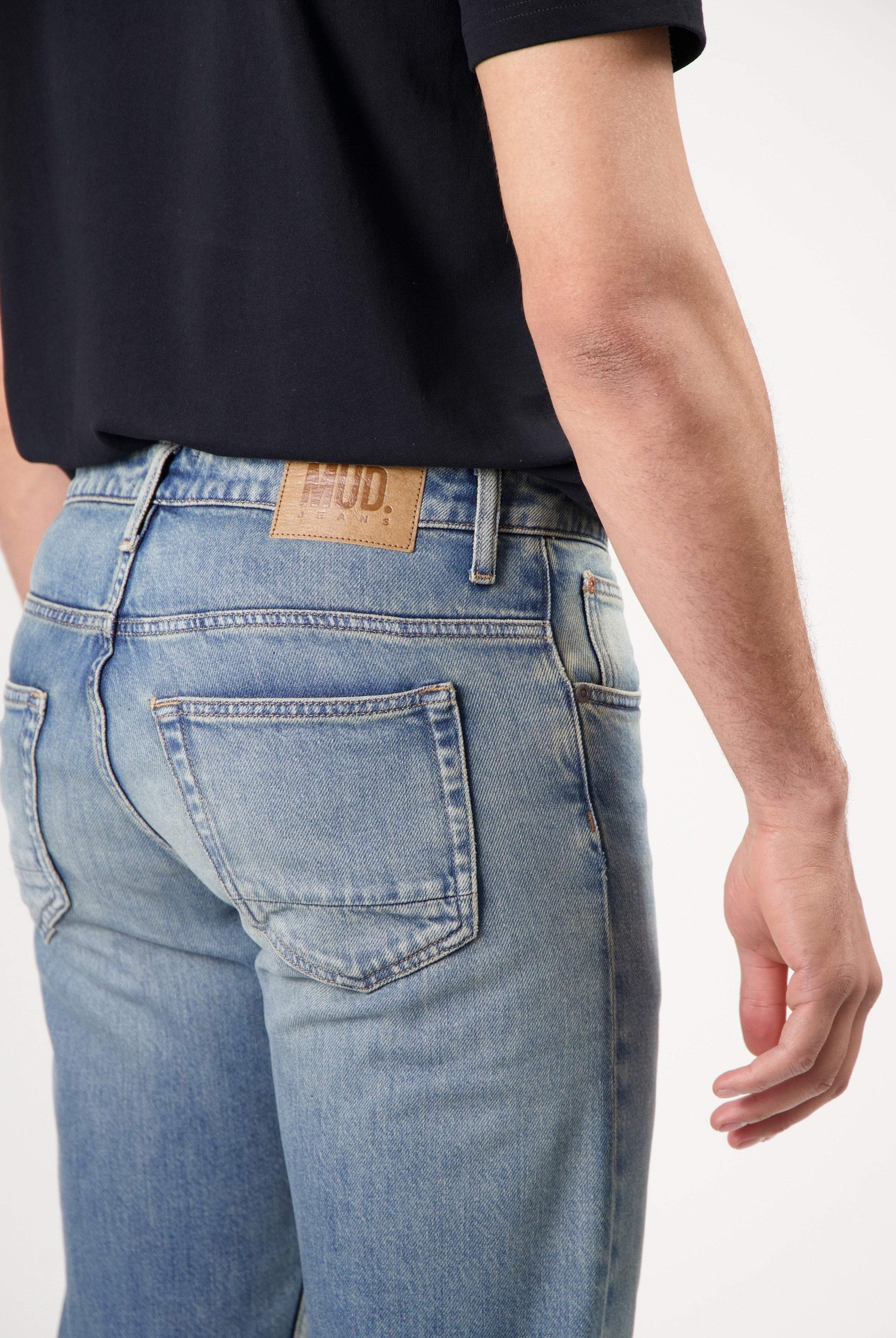 Sustainable MUD Jeans navy t-shirt paired with matching shorts, showcasing ethical fashion with white sneakers.