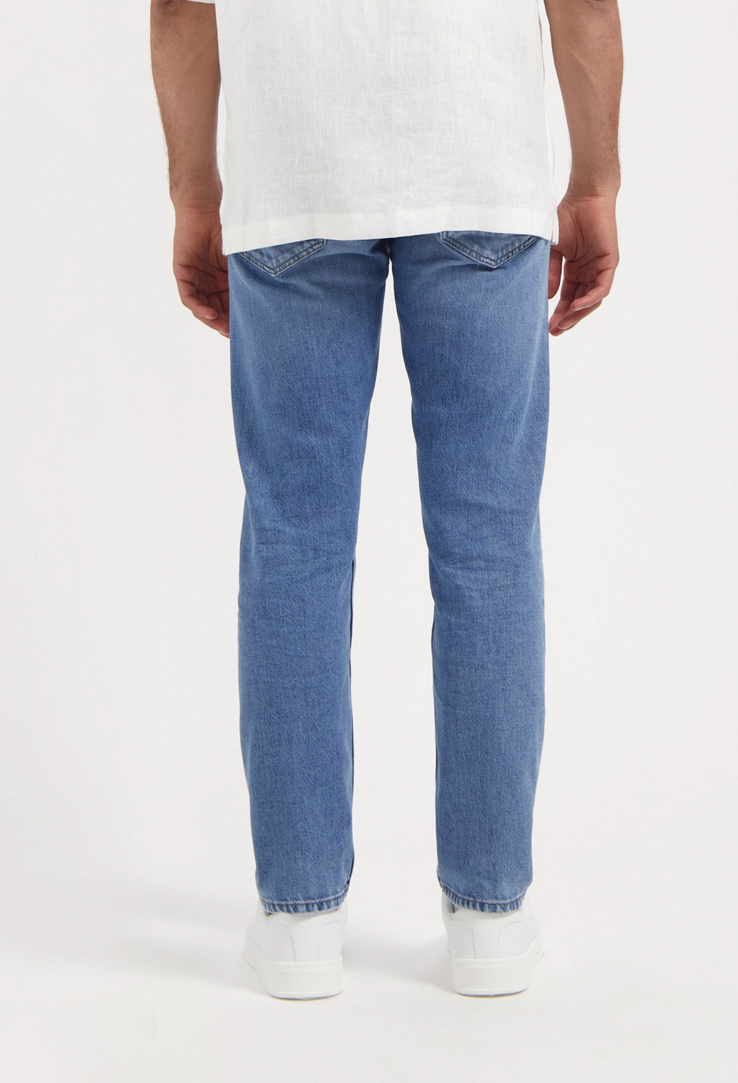 Sustainable MUD Jeans in light blue denim with a classic fit, promoting ethical fashion, paired with a black t-shirt.