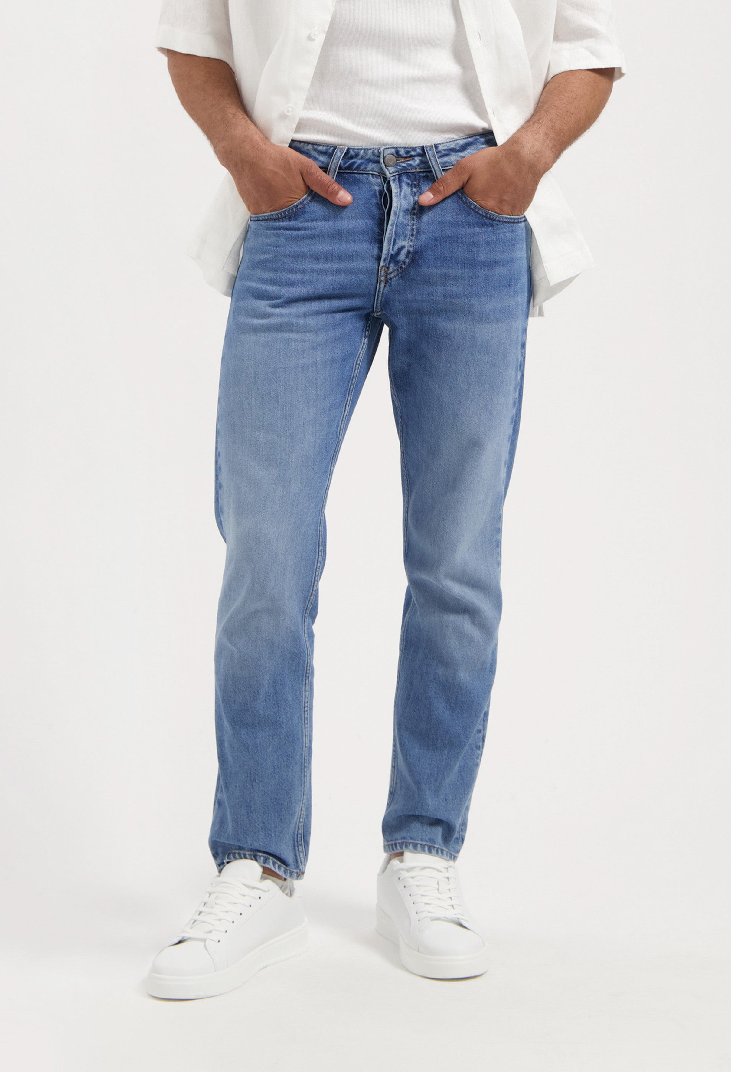 Sustainable Mud Jeans in light blue, eco-friendly organic cotton denim, styled with a classic black tee and sneakers.