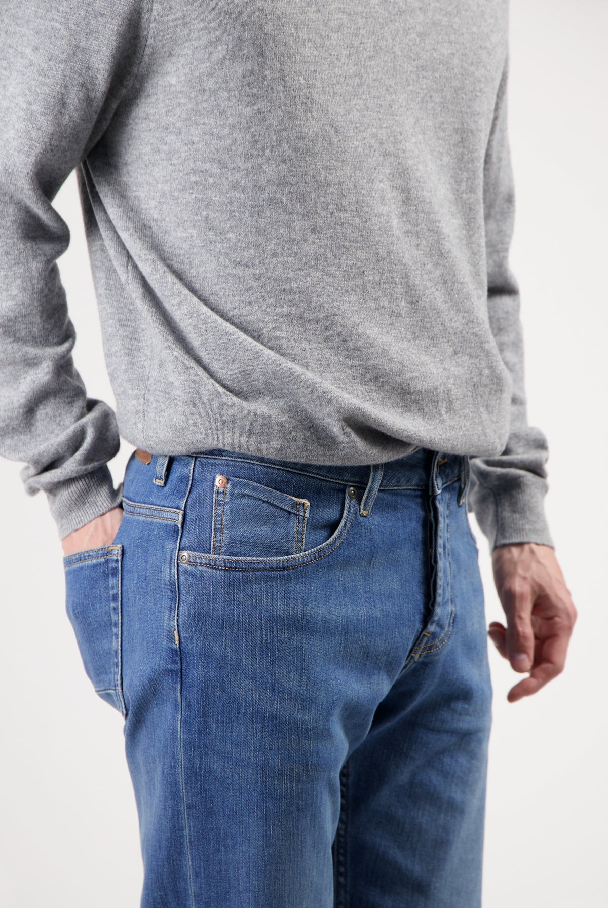 Sustainable MUD Jeans in deep blue denim, crafted from organic cotton, paired with a soft gray sweater.