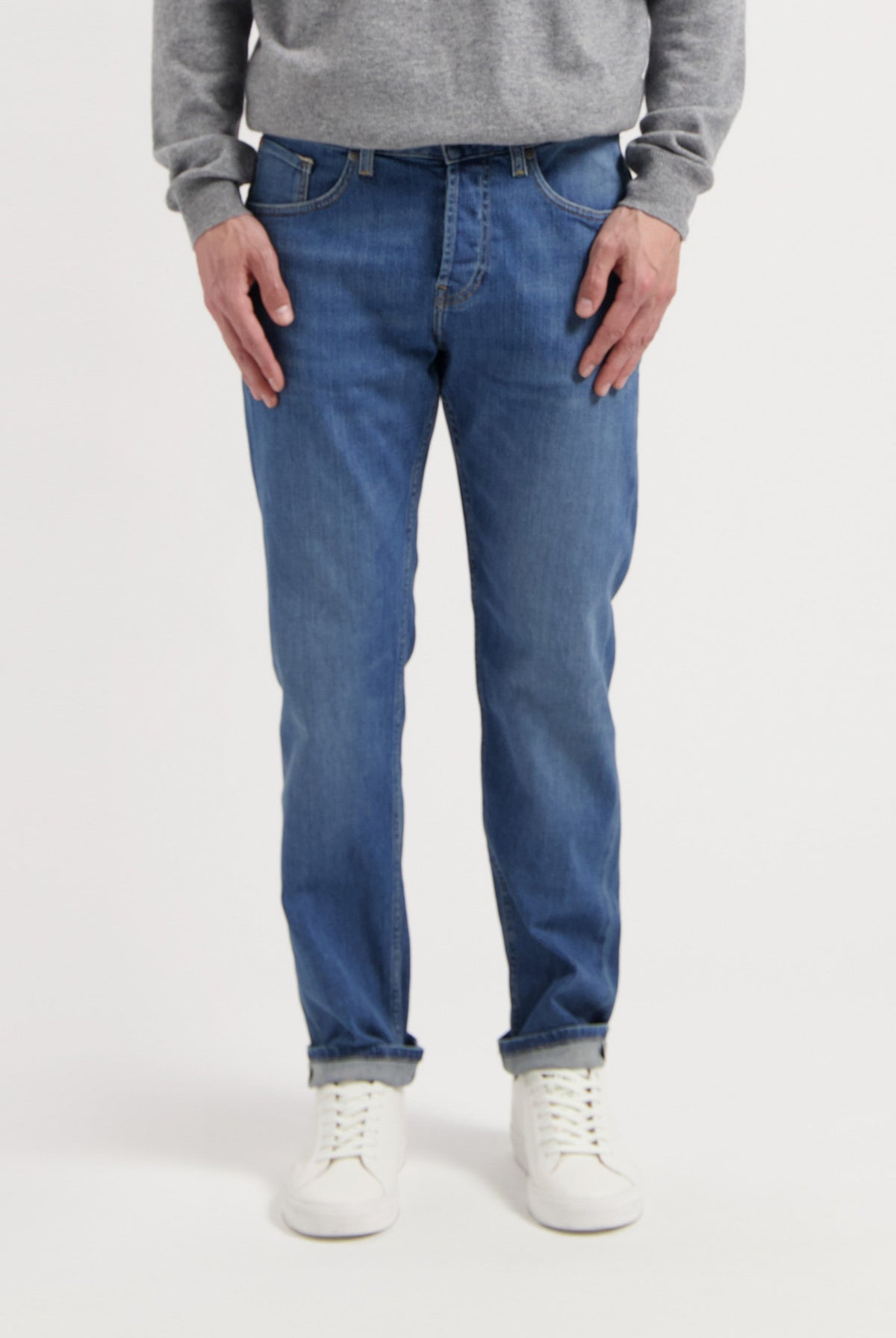 Sustainable MUD Jeans in deep blue denim, paired with an eco-friendly gray sweater and white sneakers, embody ethical fashion.
