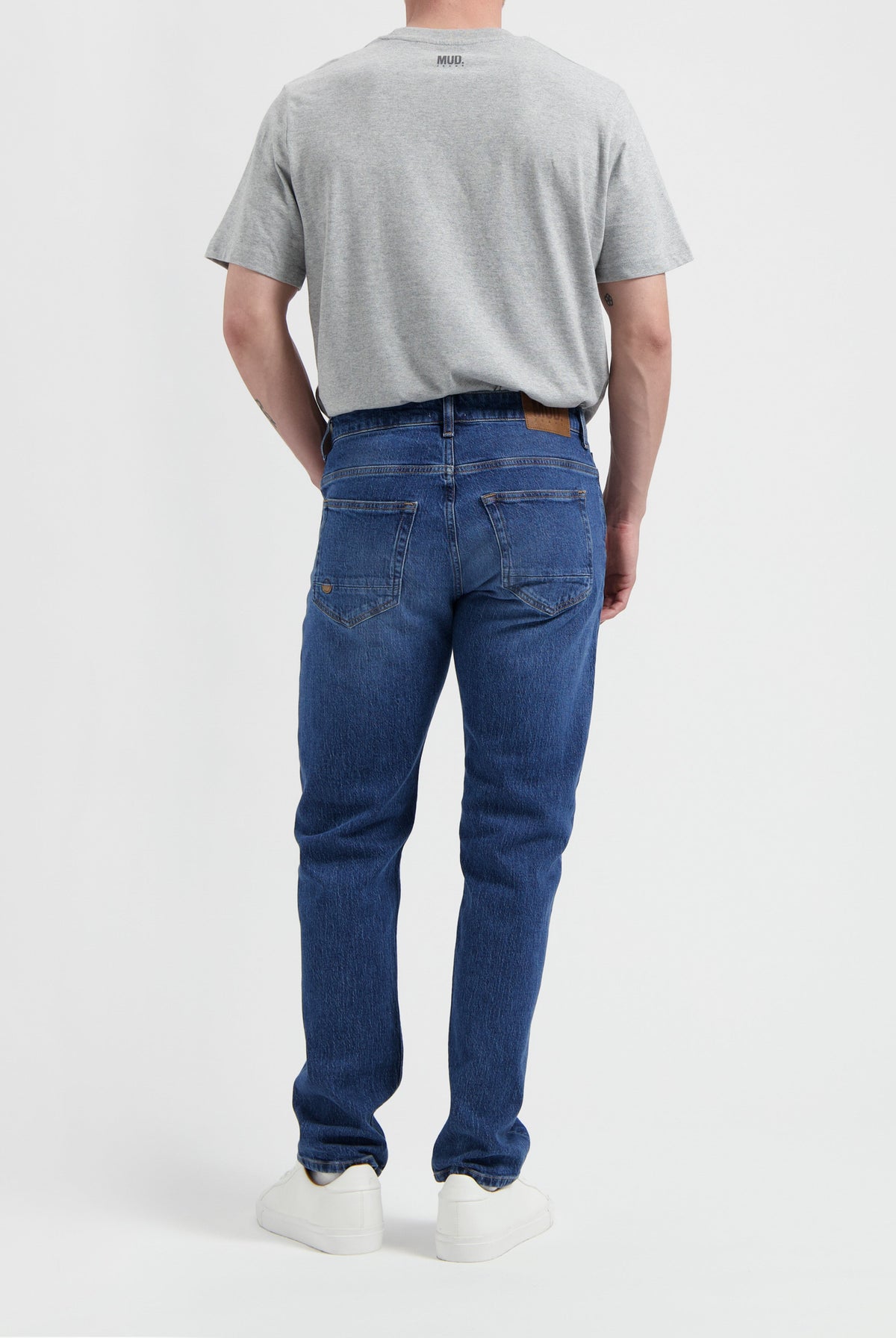 Sustainable MUD Jeans in dark blue denim, crafted ethically from organic cotton, paired with a simple white t-shirt.