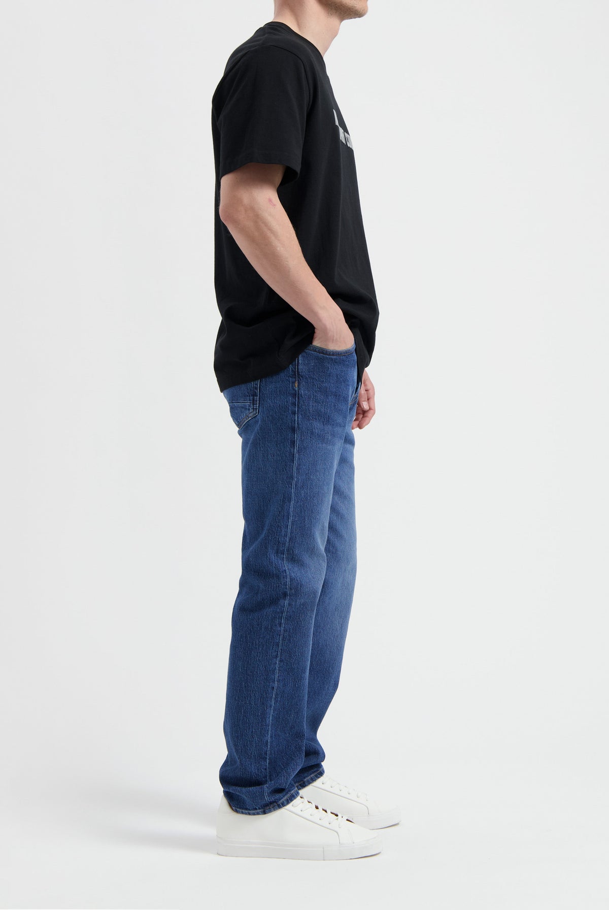 Sustainable MUD Jeans in dark denim, crafted from organic cotton, paired with a white tee and ethical white sneakers.