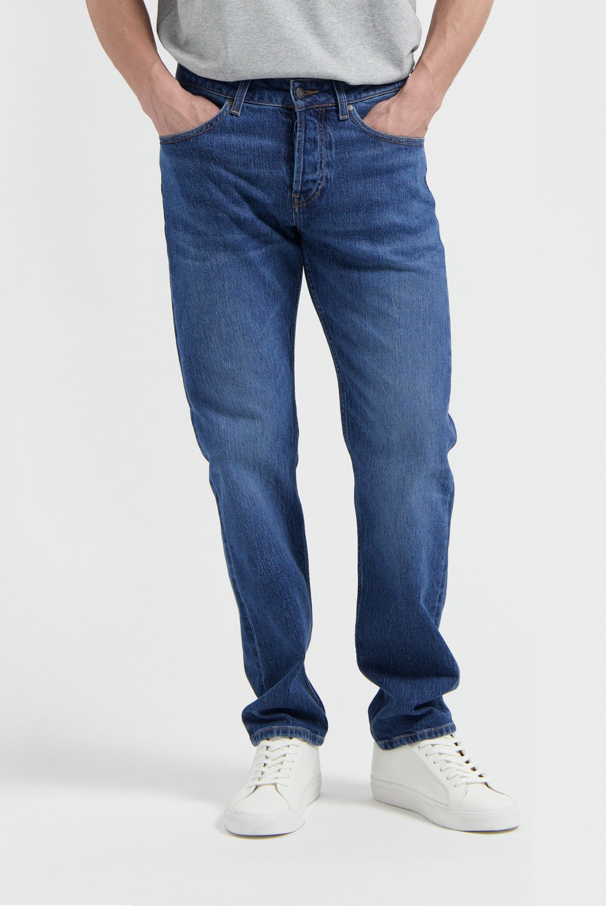 Sustainable MUD Jeans in dark blue denim, ethically made for casual wear, paired with a white t-shirt and sneakers.