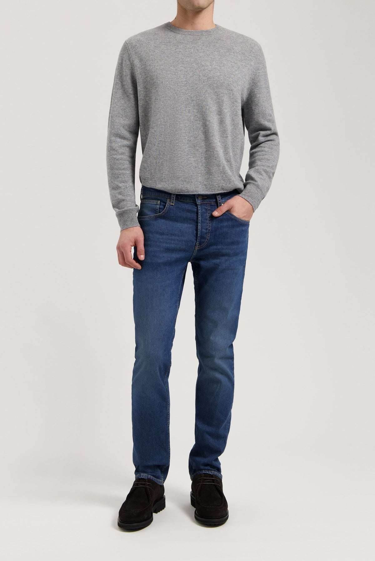 Sustainable MUD Jeans in dark blue denim, crafted from organic cotton, styled with a classic gray sweater for an ethical look.