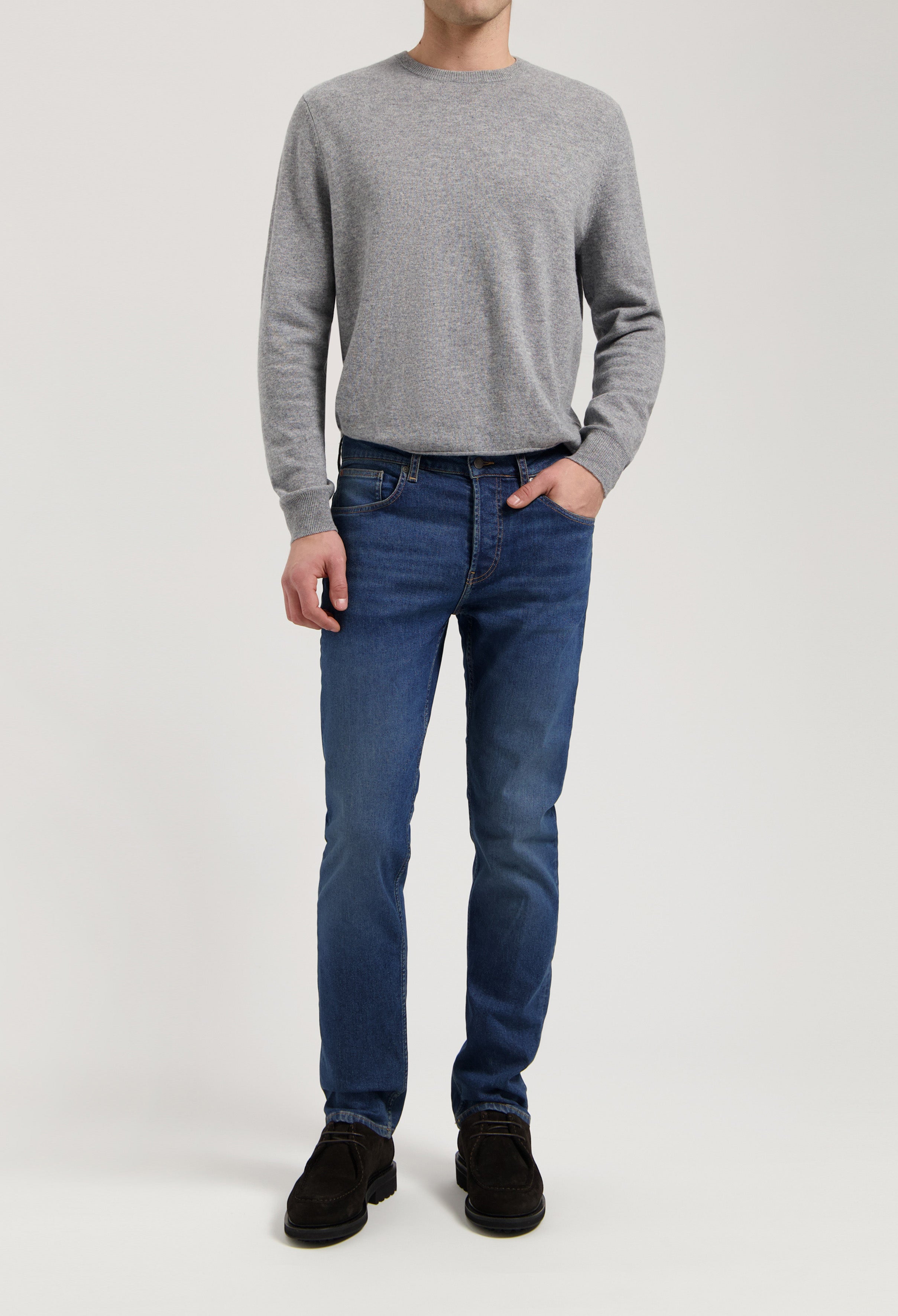 Sustainable MUD Jeans in dark blue denim, crafted from organic cotton, styled with a classic gray sweater for an ethical look.