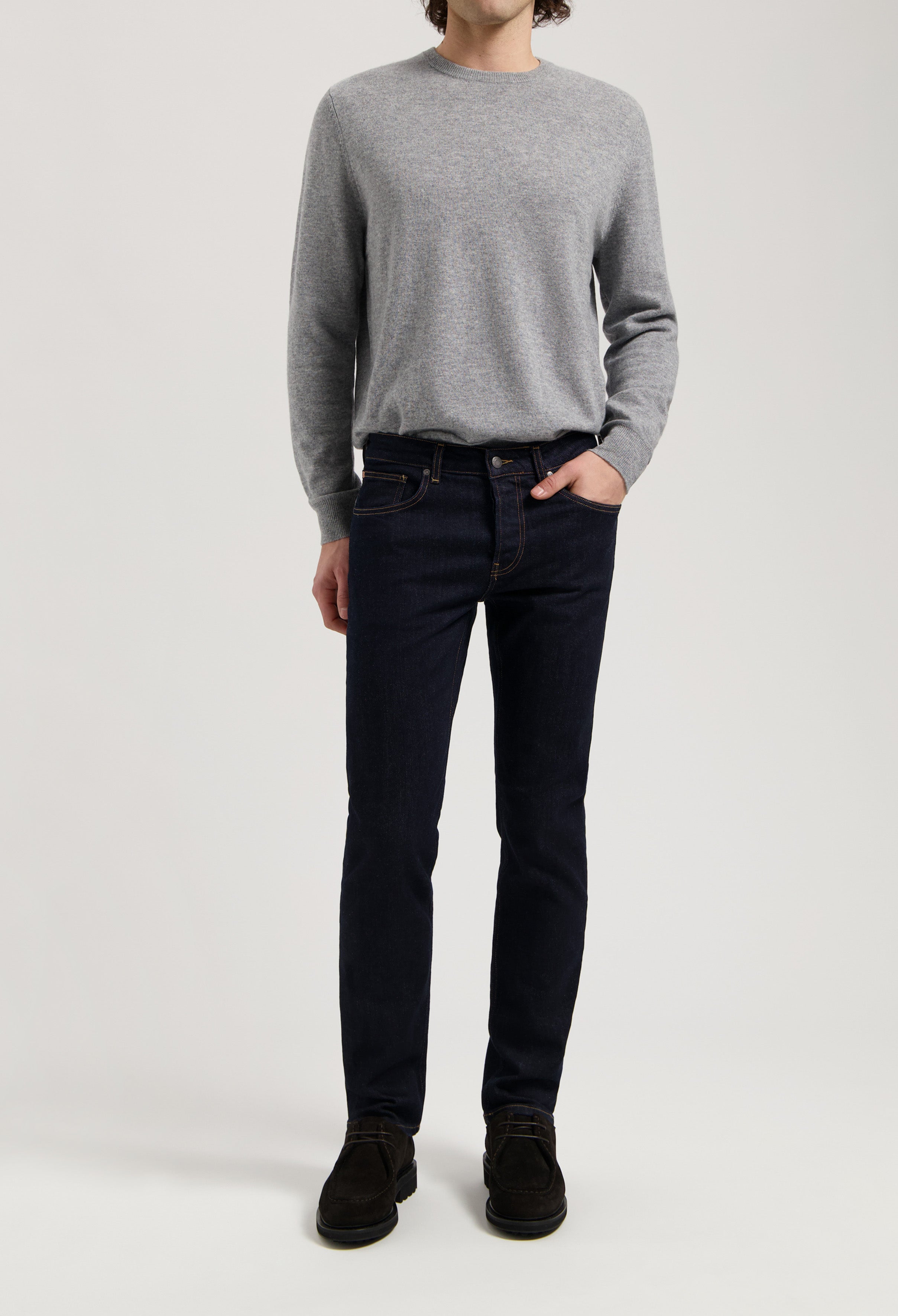 Sustainable MUD Jeans in dark blue denim, paired with a casual gray sweater, crafted from organic cotton.