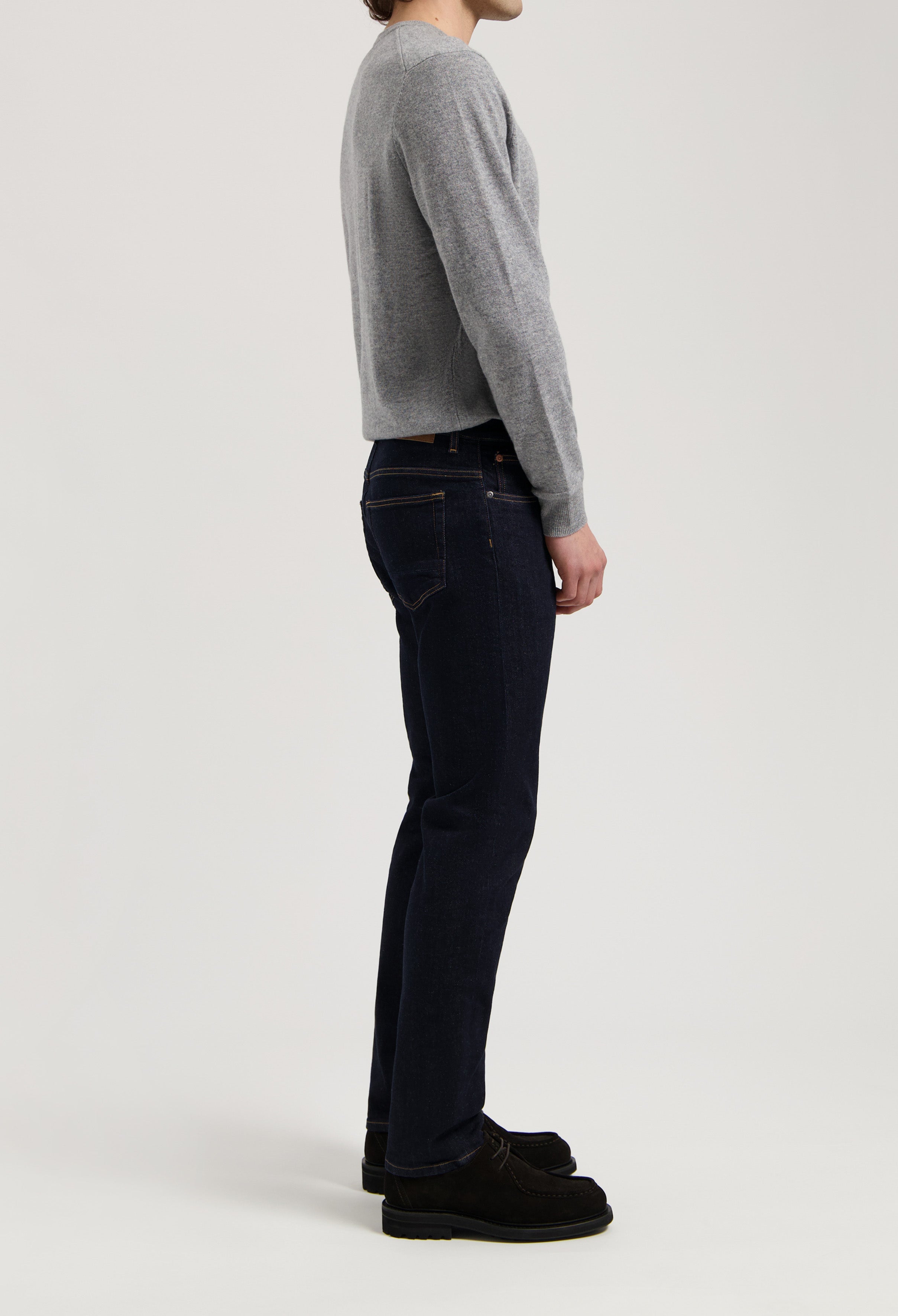 Sustainable MUD Jeans in dark indigo, crafted from organic cotton, classic fit, paired with a soft gray sweater.