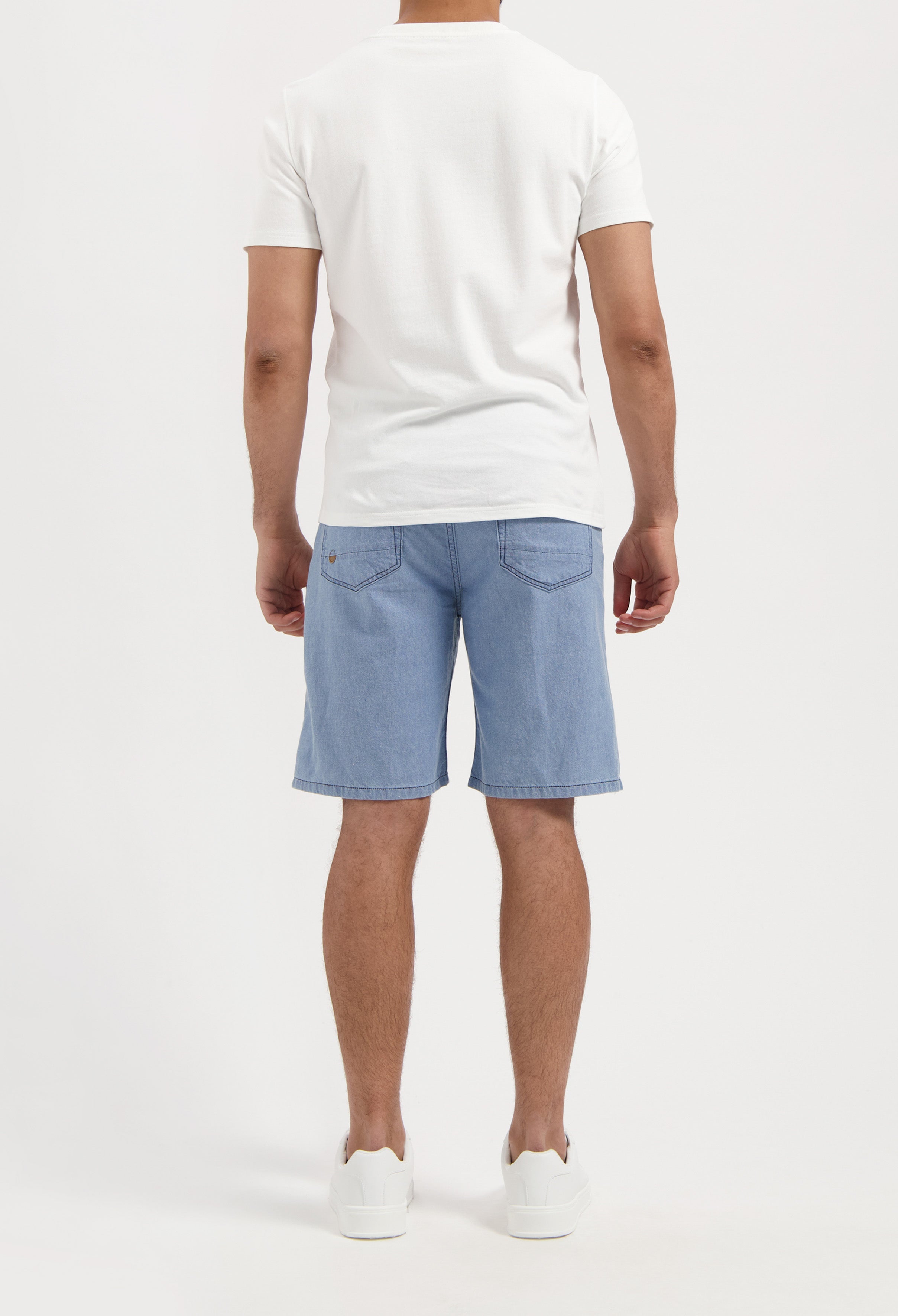 Sustainable MUD Jeans in dark denim with a slim fit, paired with a casual gray sweater and white sneakers.