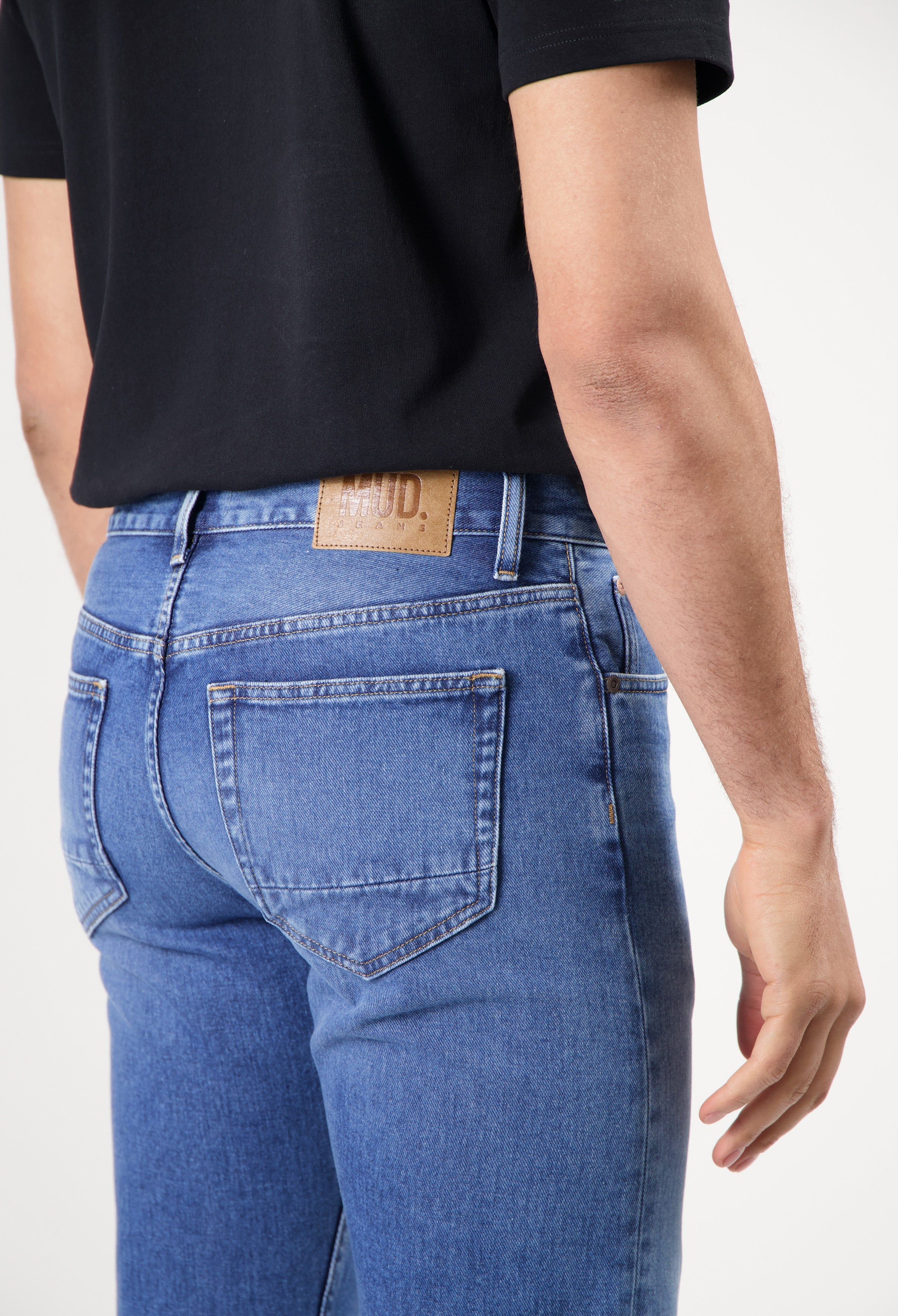 Sustainable MUD Jeans in dark wash denim, featuring relaxed fit and ethical craftsmanship, paired with a white t-shirt.