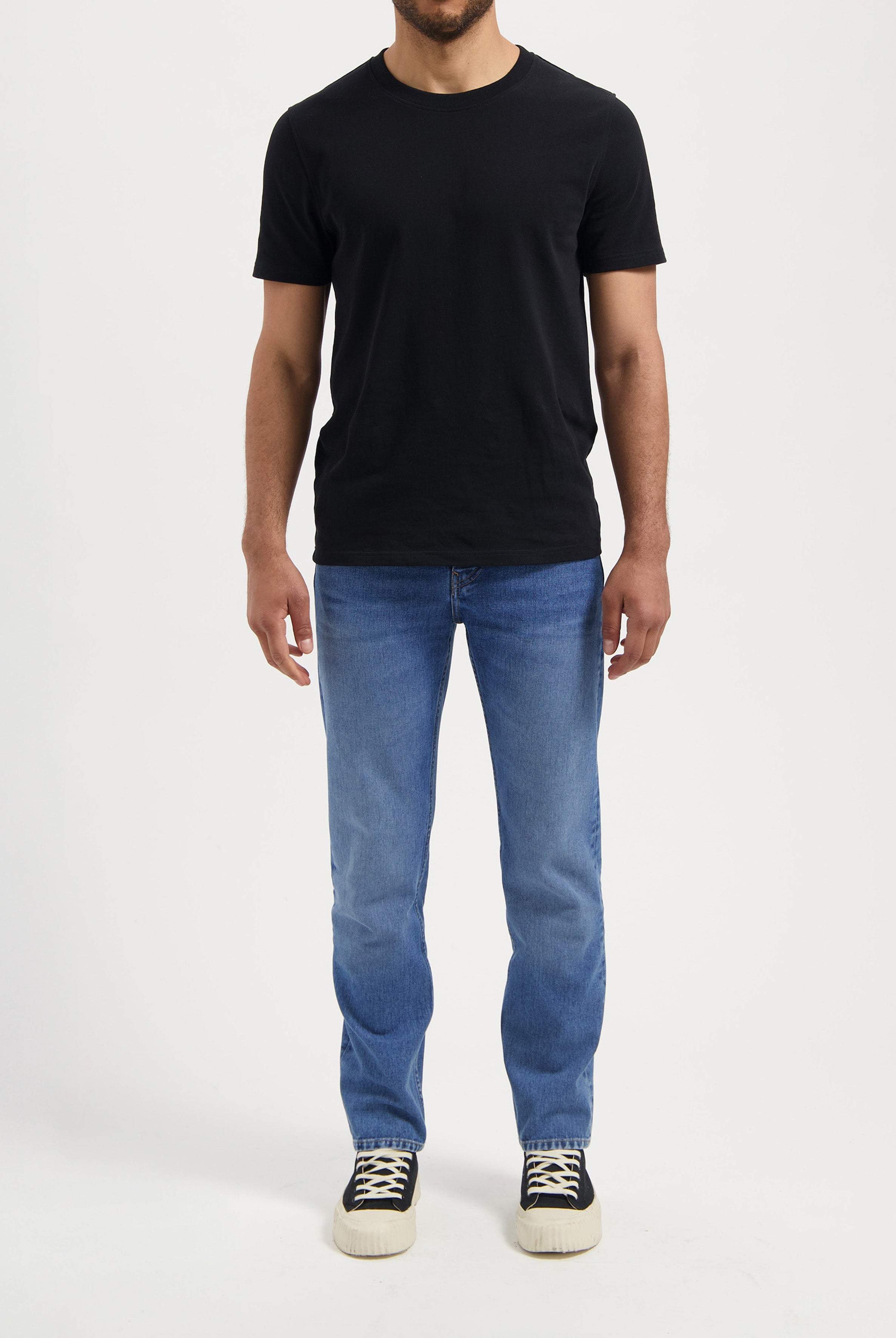 Sustainable MUD Jeans in light blue denim, ethically made, viewed from back, paired with a black shirt.