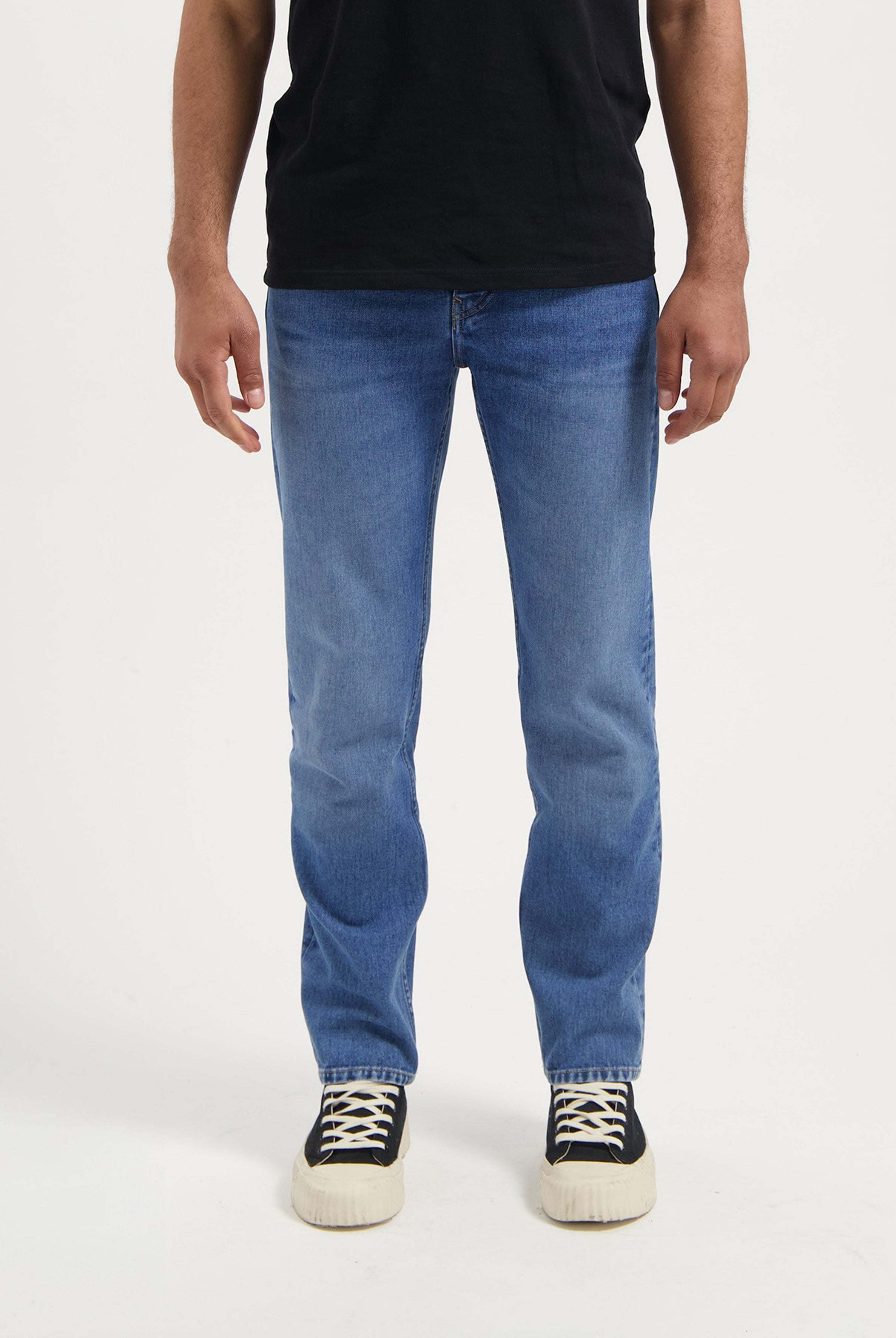 Sustainable black MUD Jeans made from organic cotton, featuring a relaxed fit and paired with a white tee.