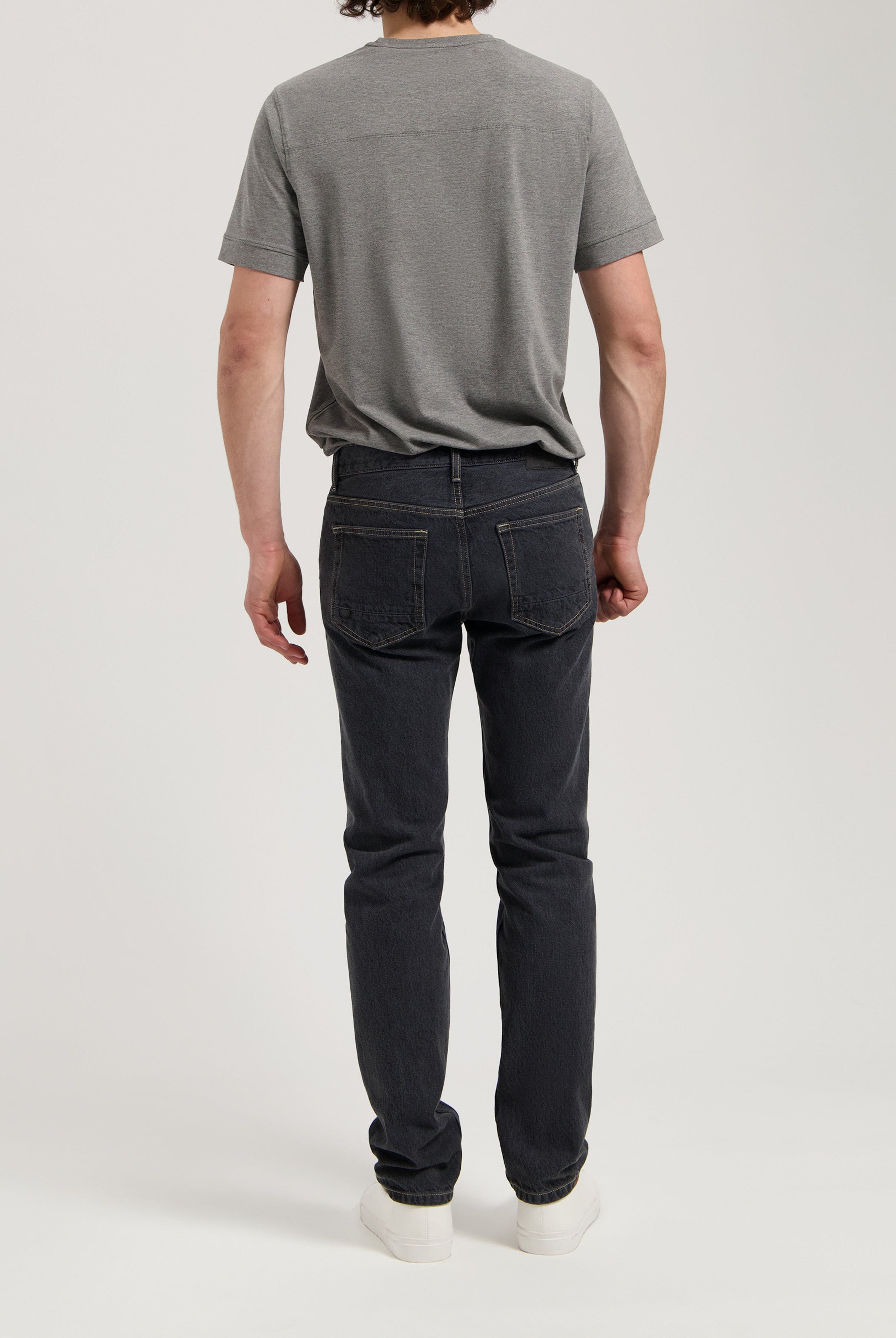 Sustainable MUD Jeans in dark denim, showcasing a comfortable ethical fit, paired with a white ribbed sweater.