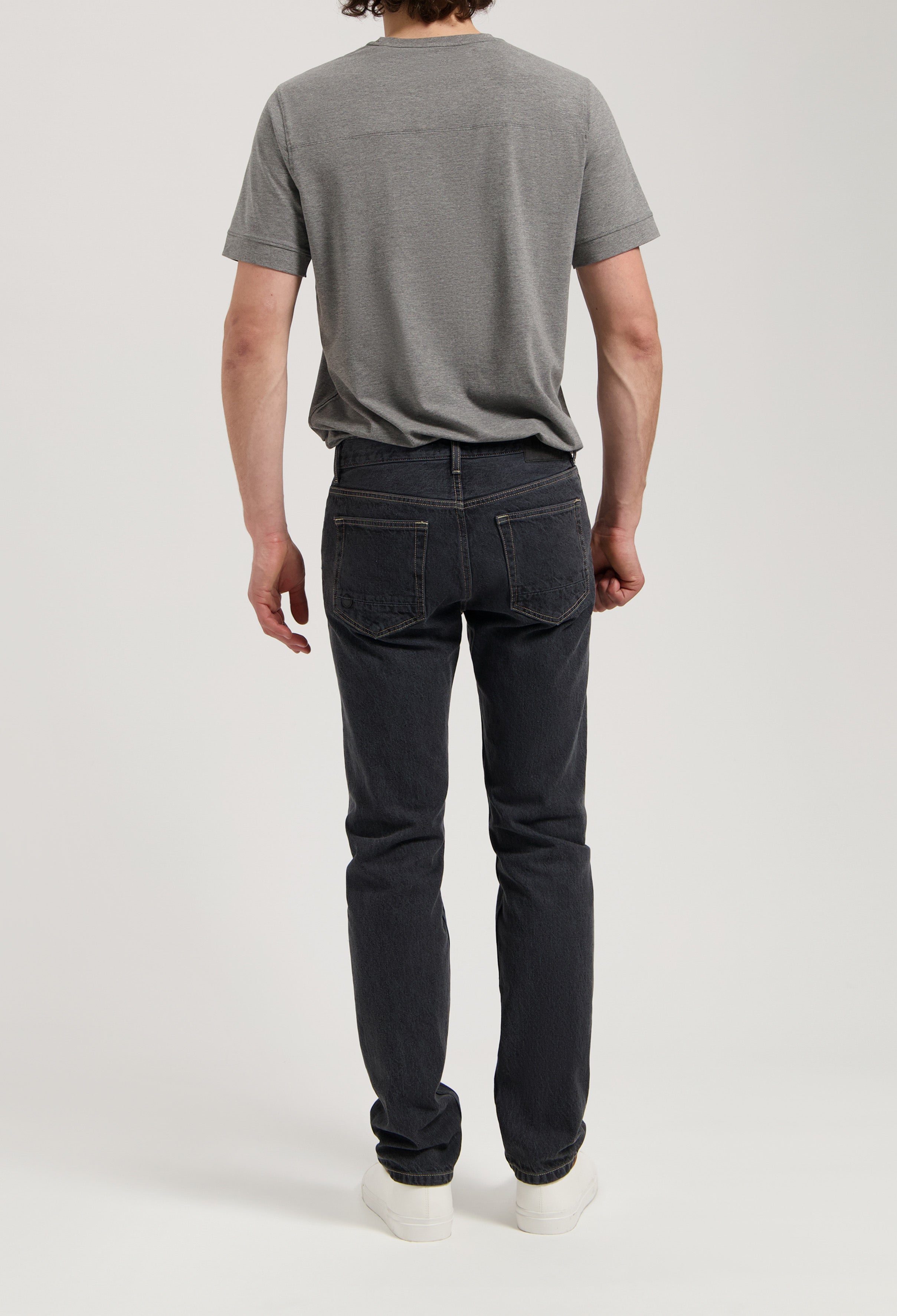 Sustainable MUD Jeans in dark denim, showcasing a comfortable ethical fit, paired with a white ribbed sweater.