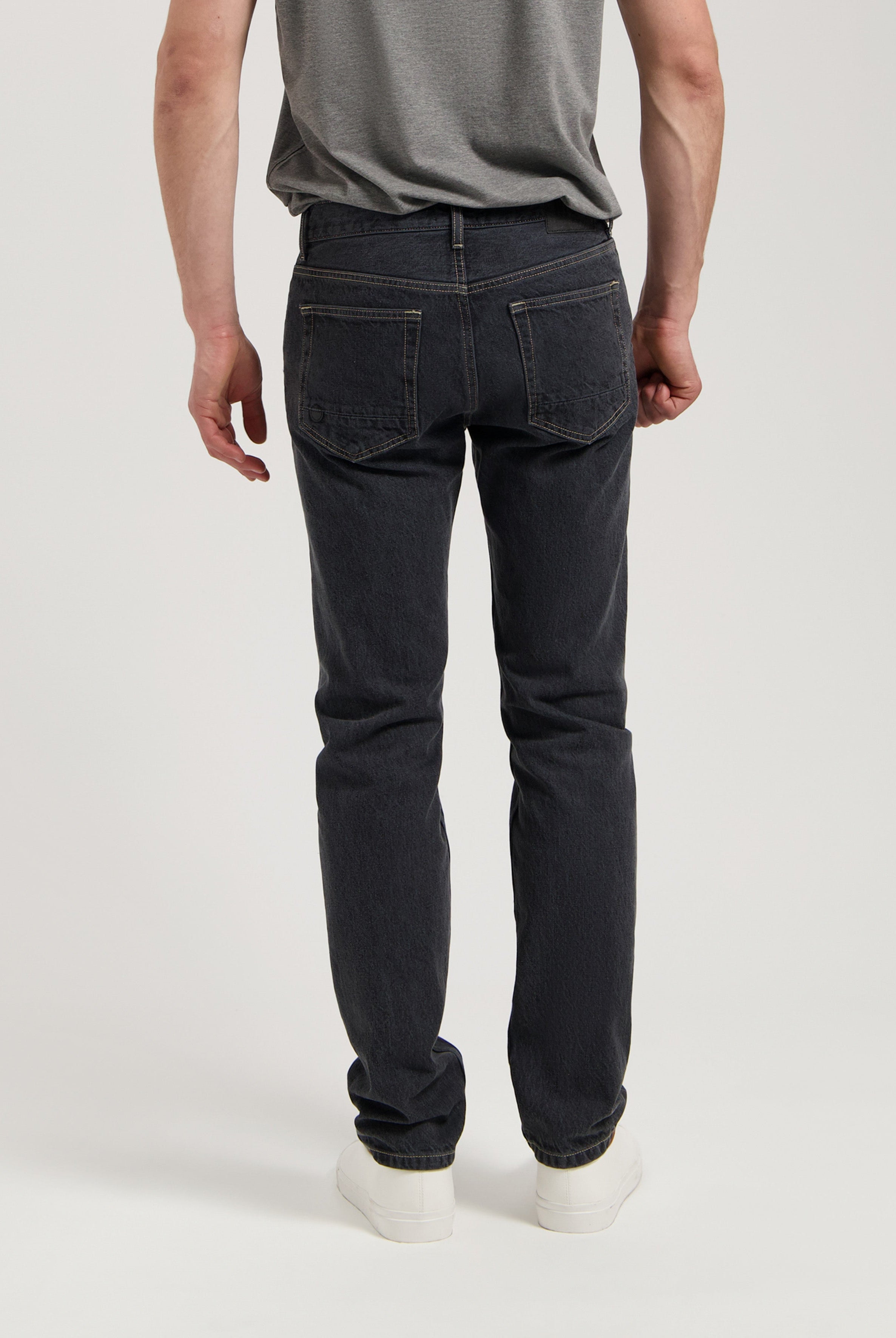 Sustainable MUD Jeans in dark denim, ethical fashion with slim fit, paired with an eco-friendly cream sweater.