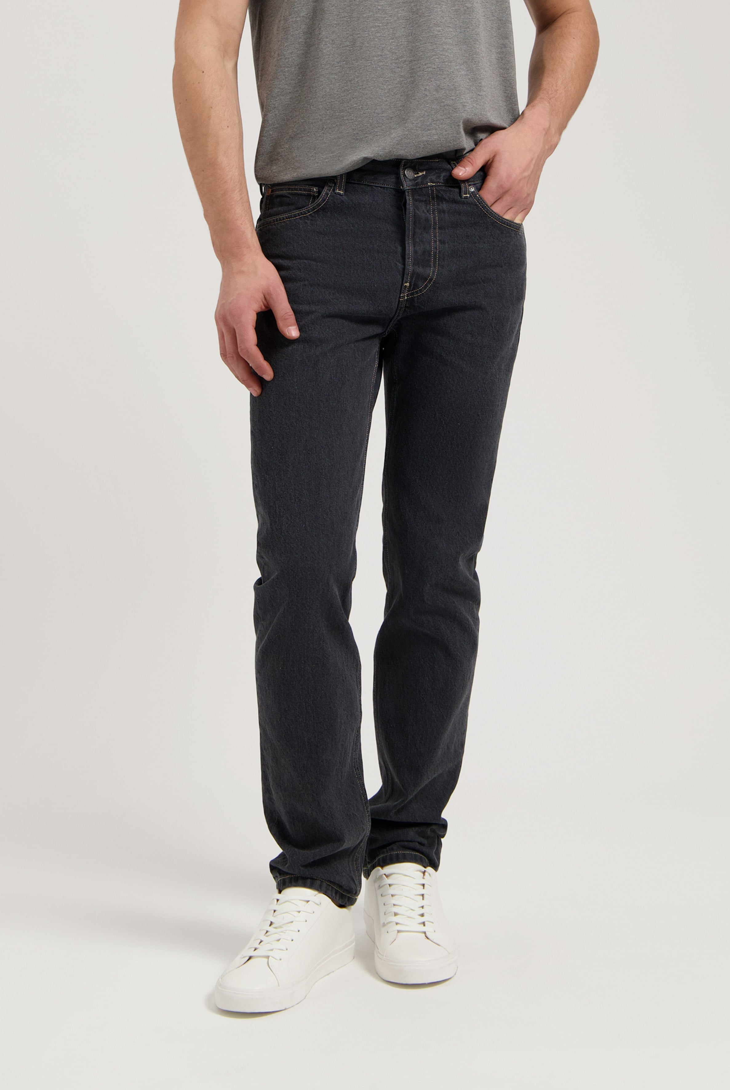 Sustainable MUD Jeans in dark denim, ethically made with organic cotton, paired with black loafers and white ribbed sweater.