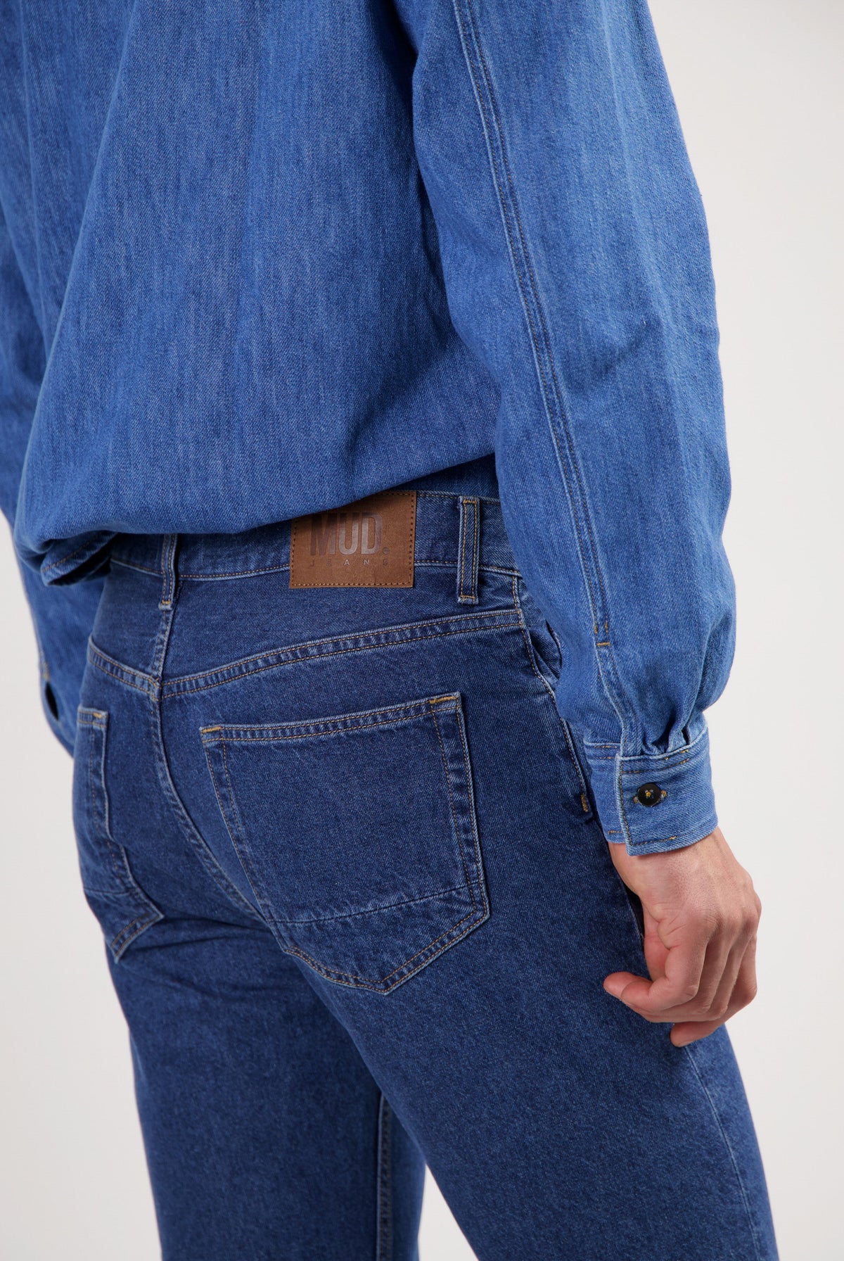 Sustainable MUD Jeans made from ethical denim, featuring dark blue material, paired with a casual white shirt.