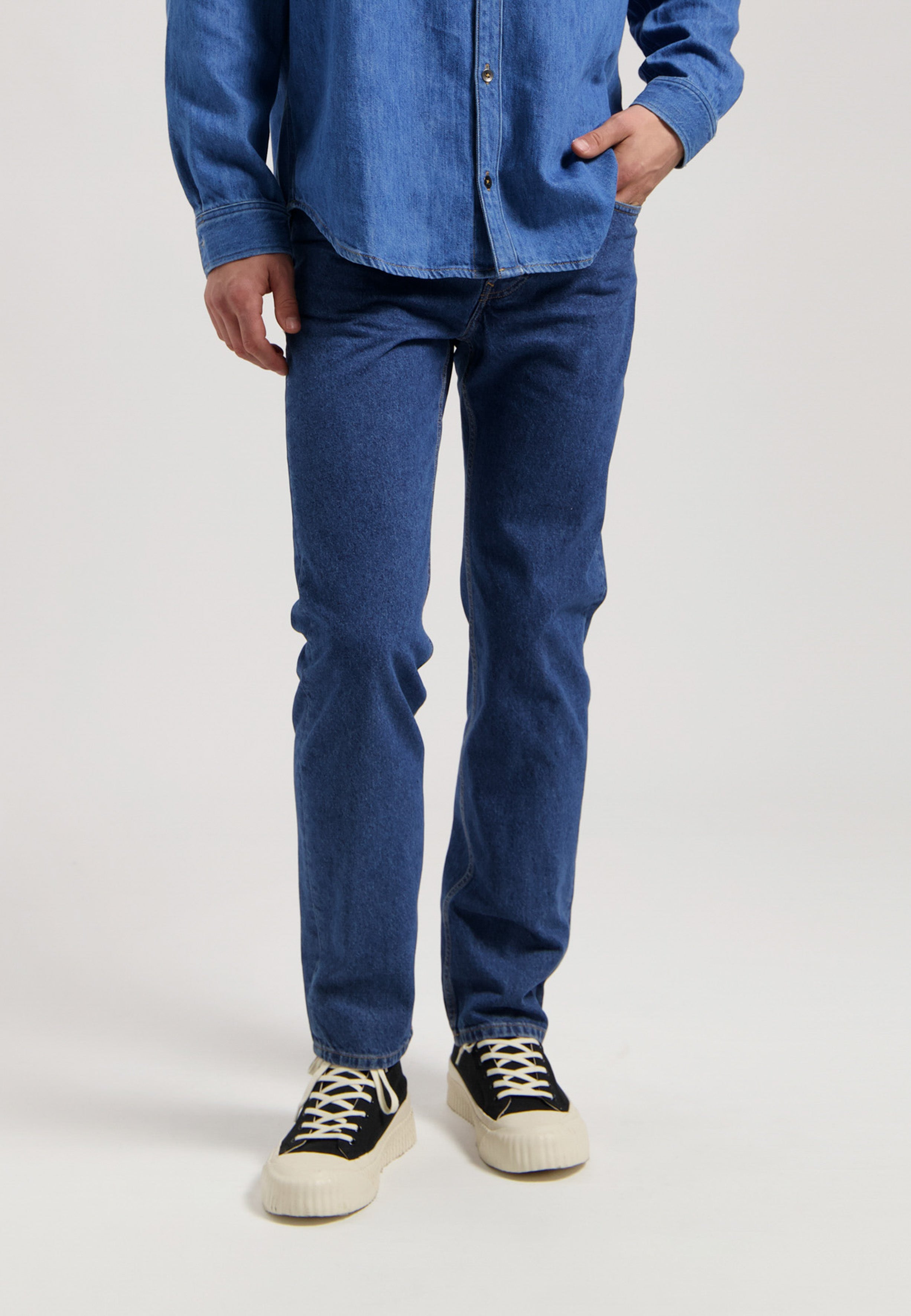 Sustainable MUD Jeans in dark blue denim, crafted ethically, paired with white shirt, showcasing classic fit style.