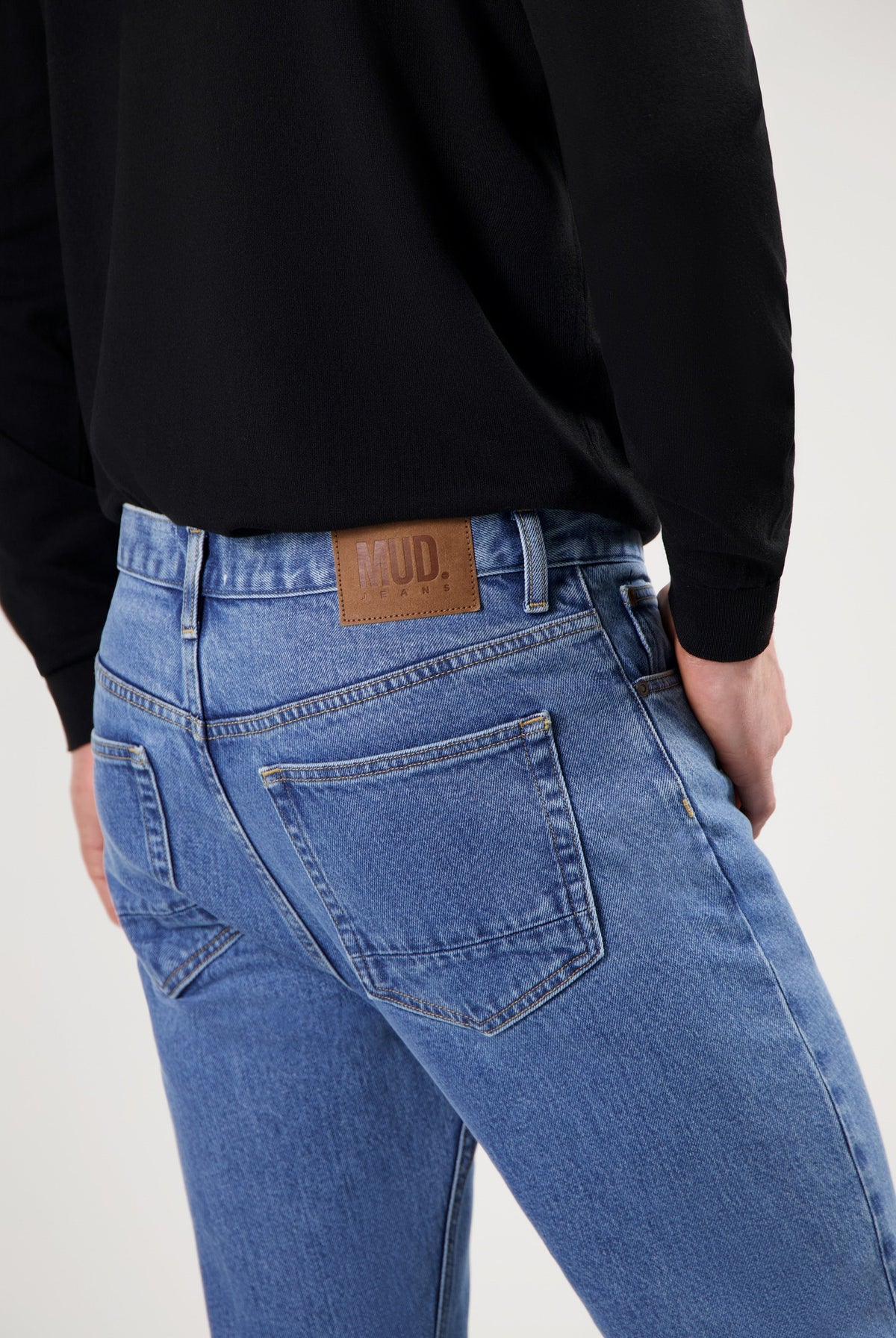 Sustainable MUD Jeans in blue denim, featuring a classic cut and ethical design, worn with a black top.