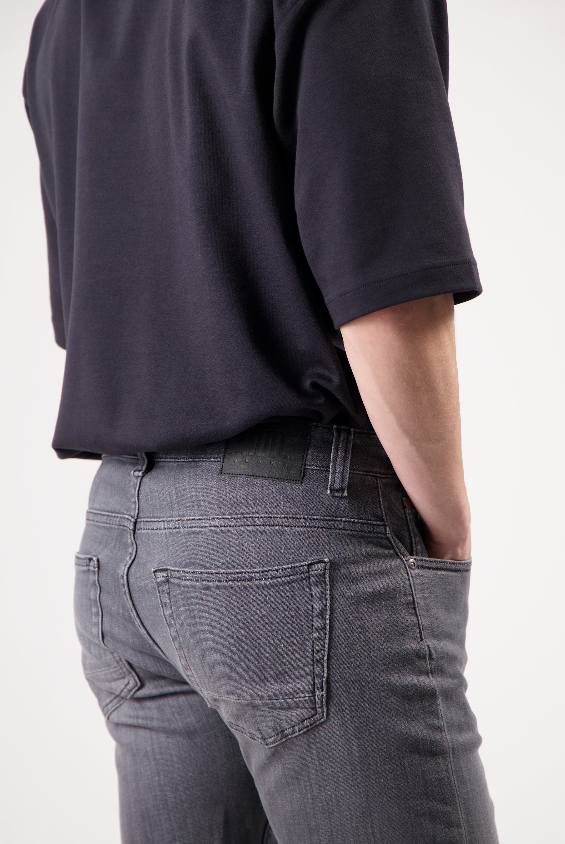 Sustainable MUD Jeans in dark blue denim, crafted ethically, paired with a casual gray T-shirt and white sneakers.