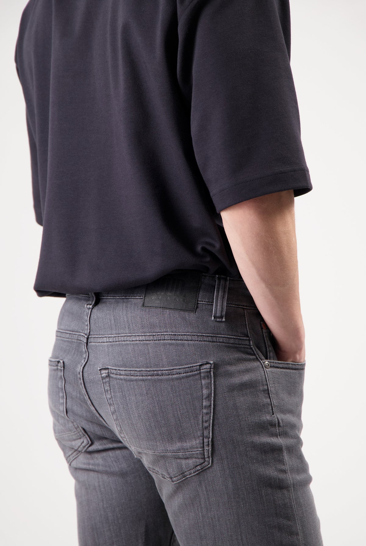 Sustainable MUD Jeans in dark blue denim, crafted ethically, paired with a casual gray T-shirt and white sneakers.
