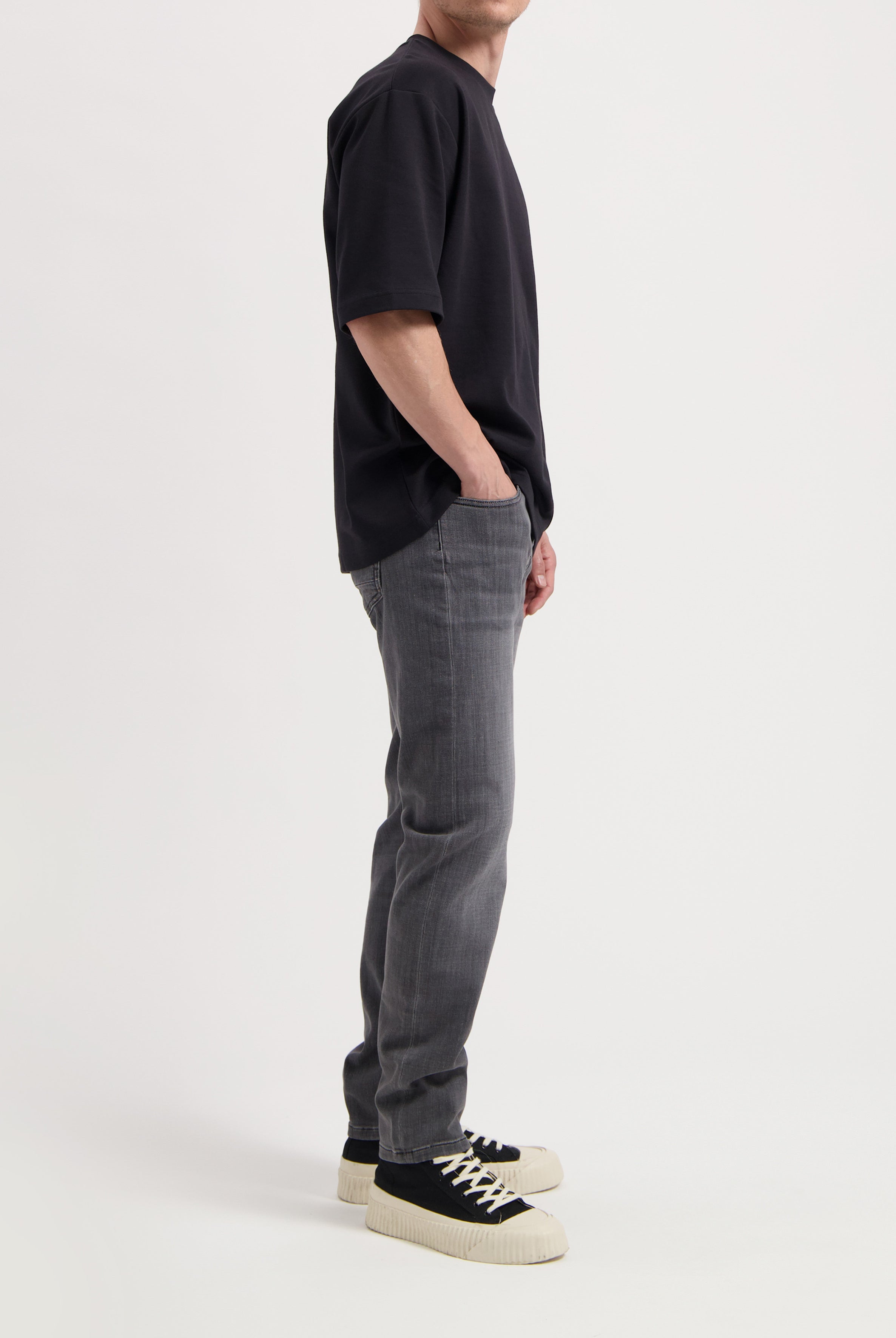 Sustainable MUD Jeans crafted from organic cotton, dark blue denim in slim fit, paired with a casual gray t-shirt.