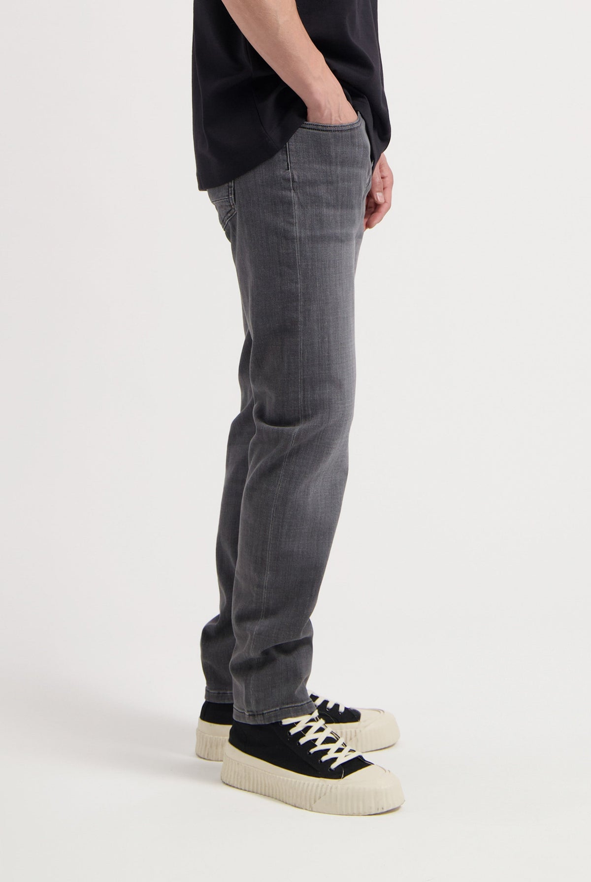 Sustainable MUD Jeans in light blue denim, crafted ethically, featuring a classic fit, paired with a white top.