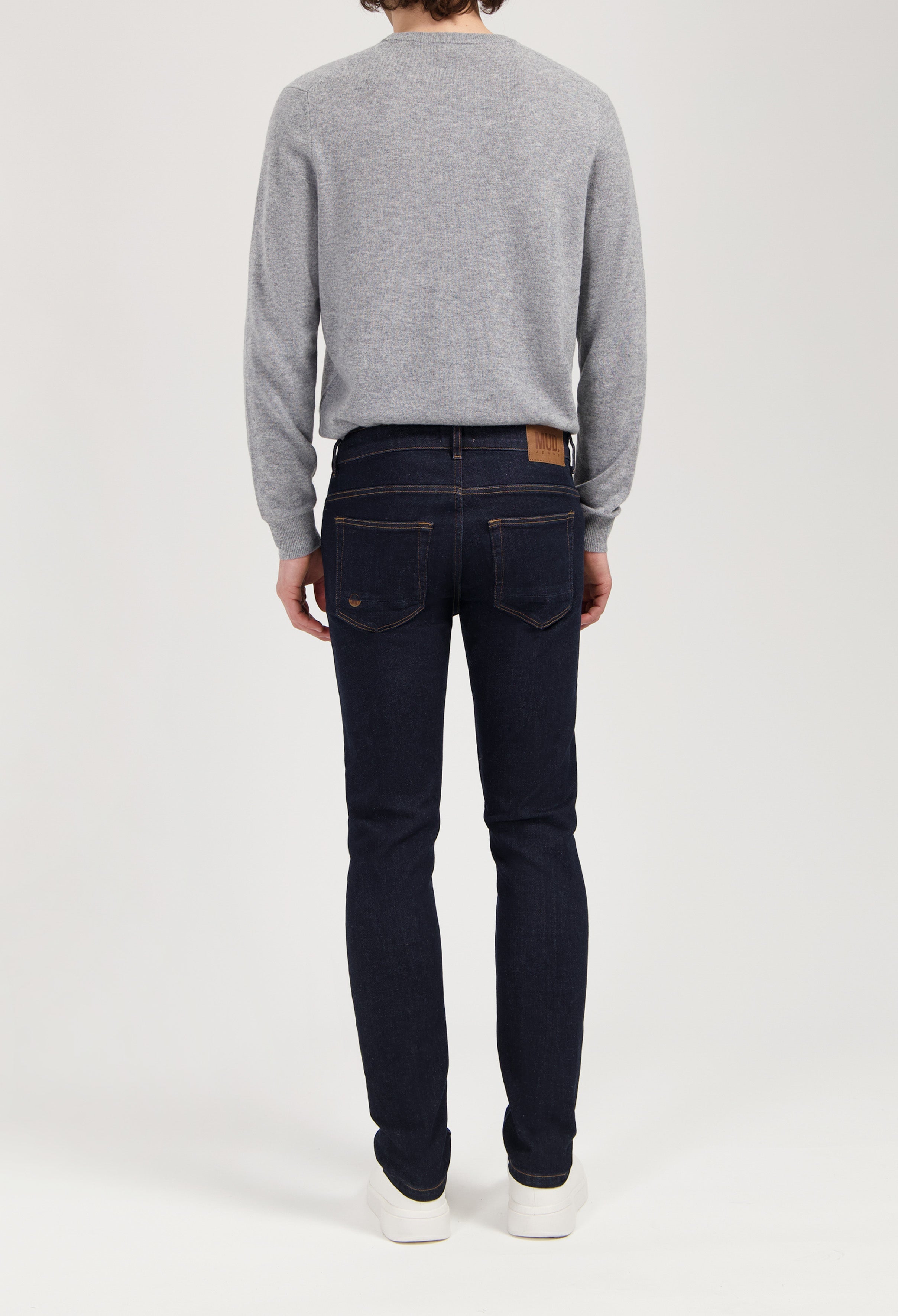 Sustainable MUD Jeans crafted from organic cotton, featuring a light blue wash and classic fit, paired with white sneakers.