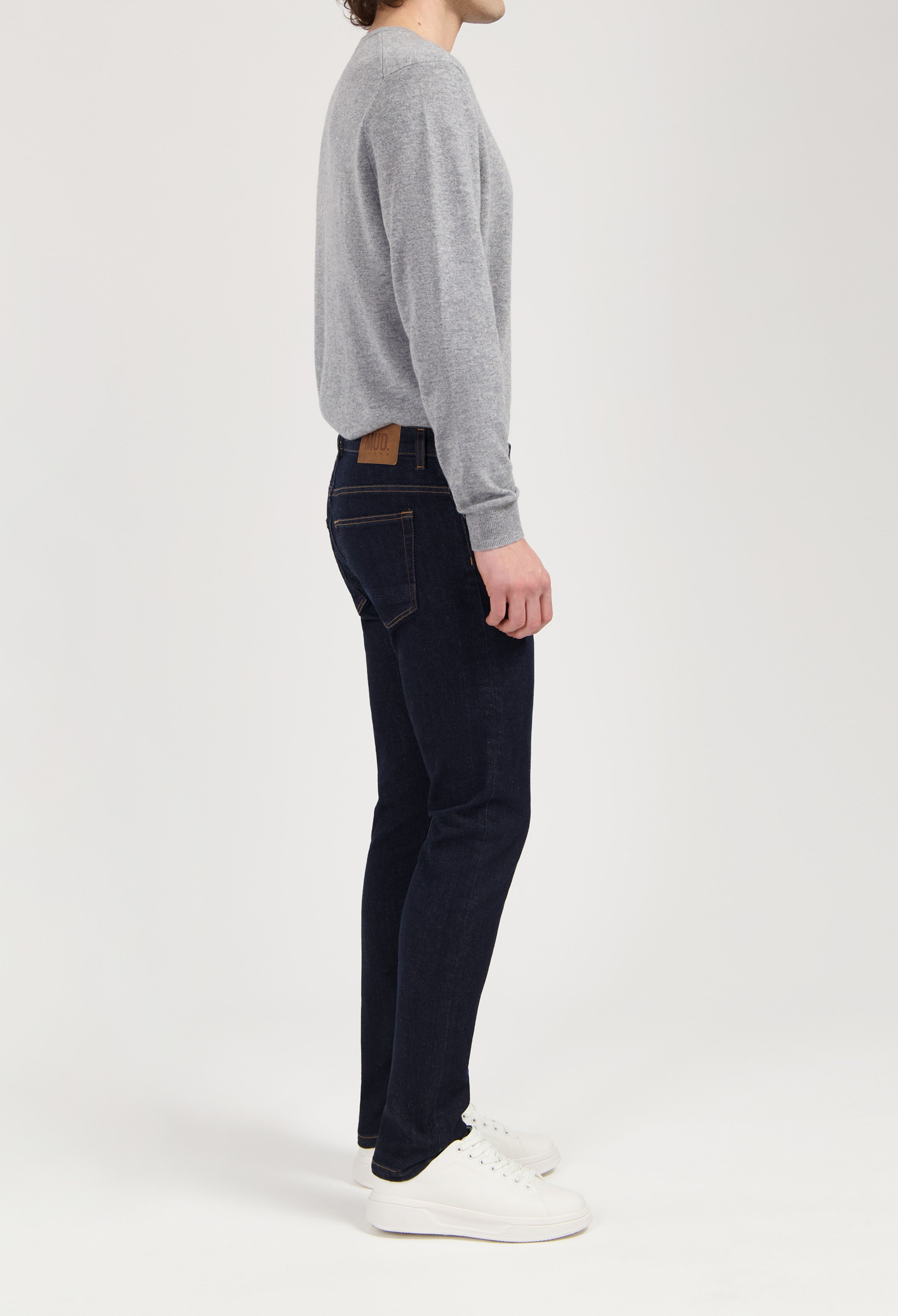Sustainable MUD Jeans in light blue denim, crafted from organic cotton, shown with a white short-sleeve shirt.