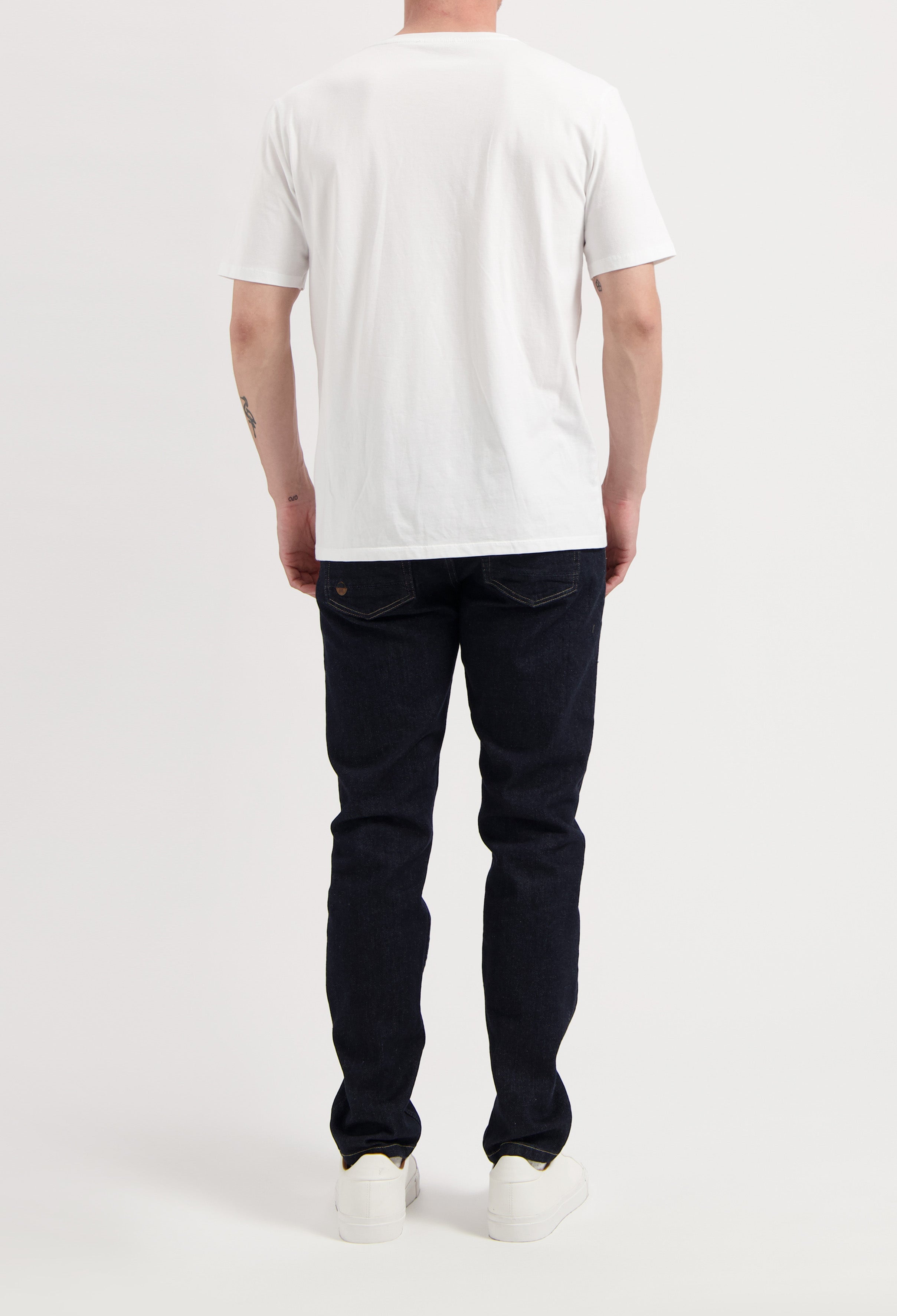Sustainable MUD Jeans in classic blue denim, crafted from organic cotton, paired with white sneakers and gray sweater.