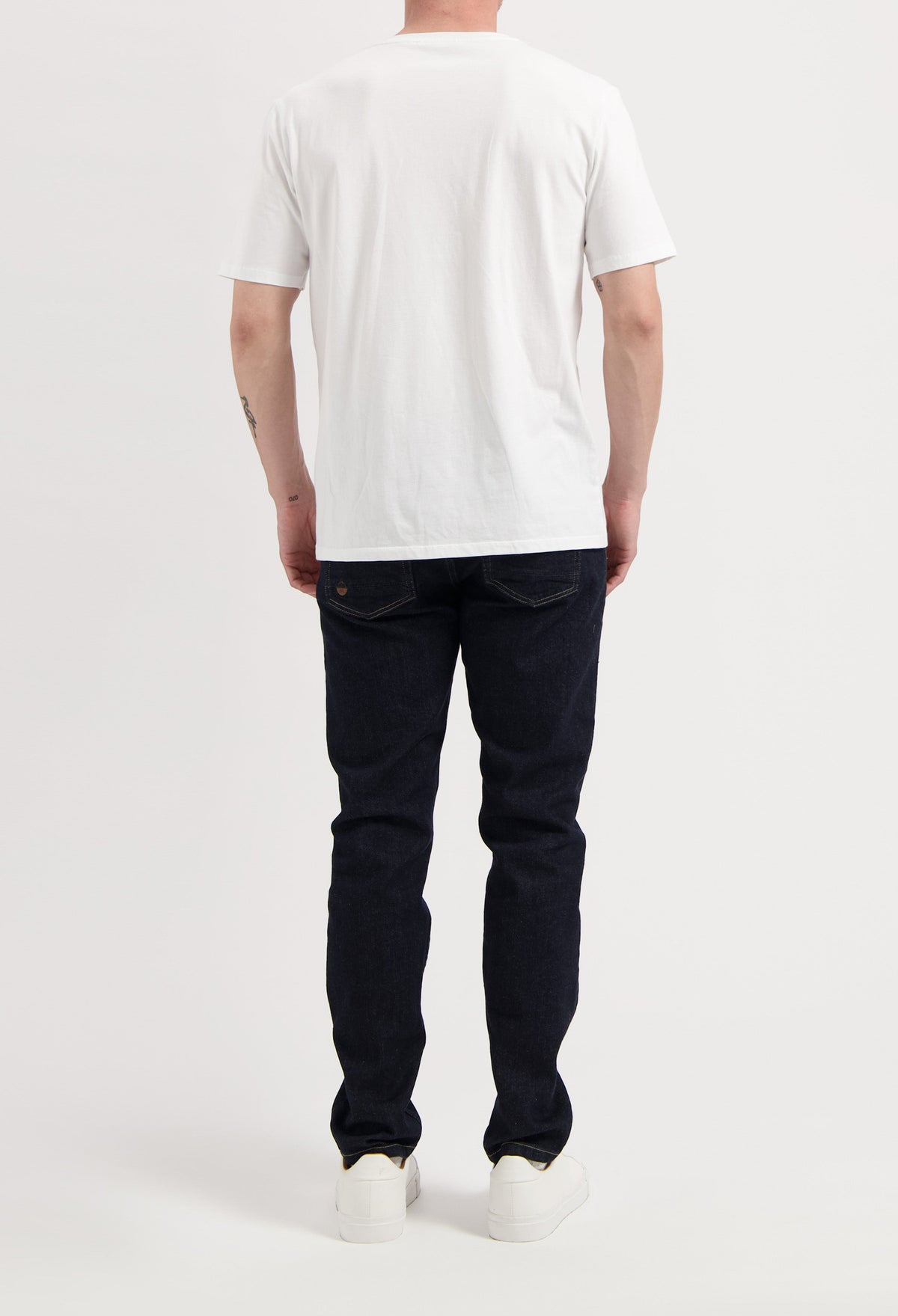 Sustainable MUD Jeans in classic blue denim, crafted from organic cotton, paired with white sneakers and gray sweater.