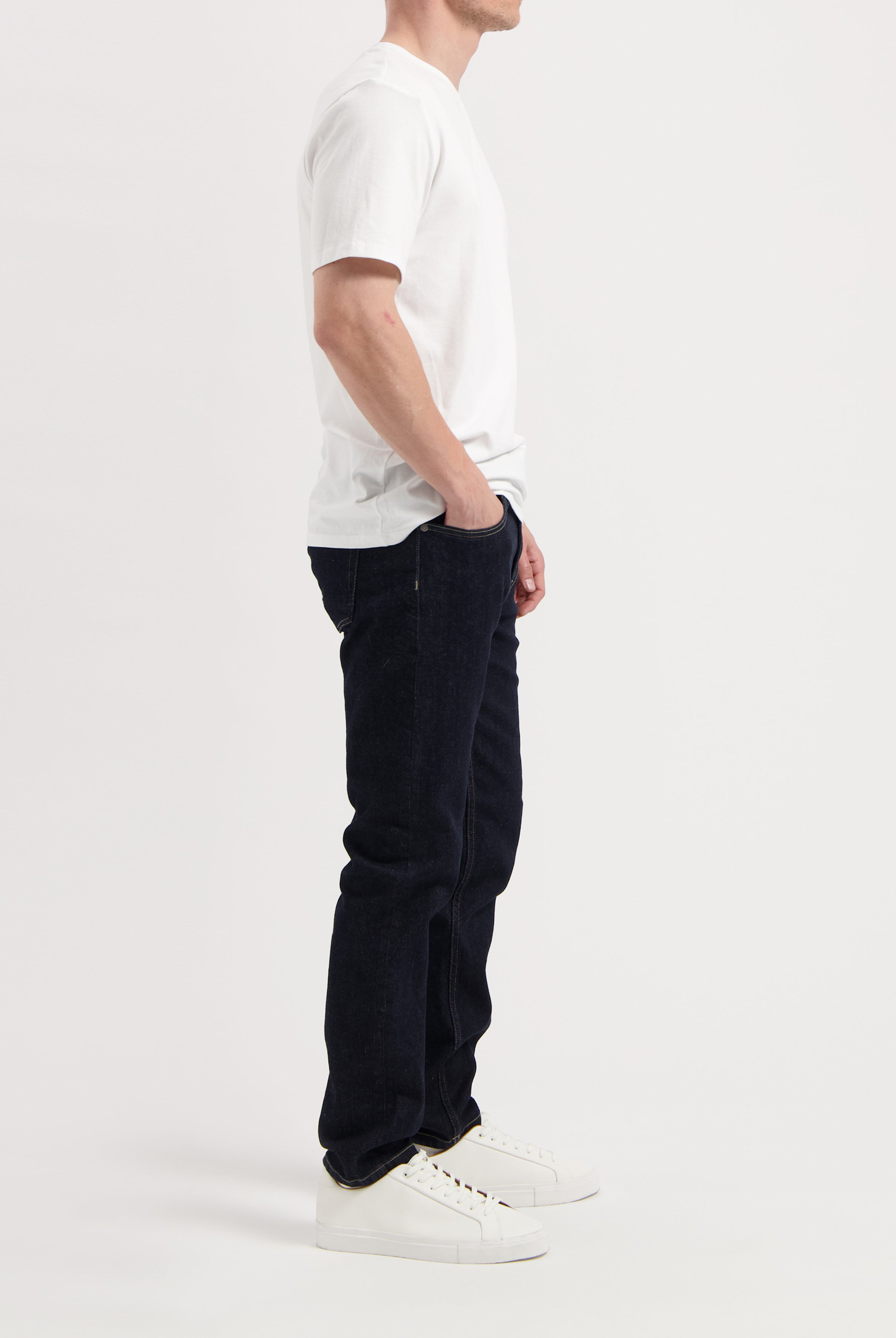 Sustainable MUD Jeans crafted from organic cotton, featuring classic blue denim in a straight fit, paired with white sneakers.