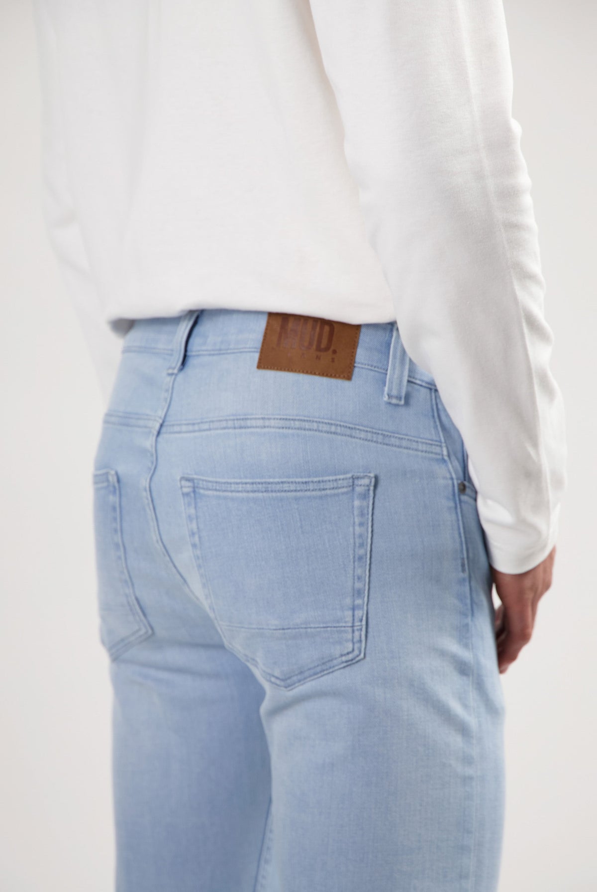 Sustainable MUD Jeans in dark denim, crafted from organic cotton, styled with black shoes and gray sweater.